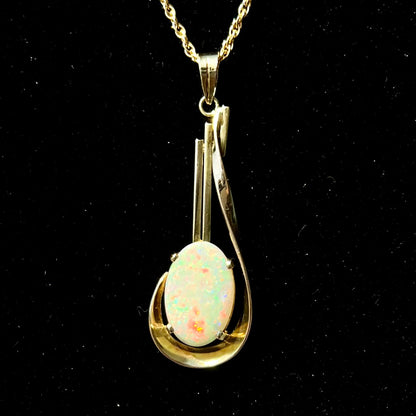 A handmade gold drop pendant set with an oval cabochon cut white crystal opal.