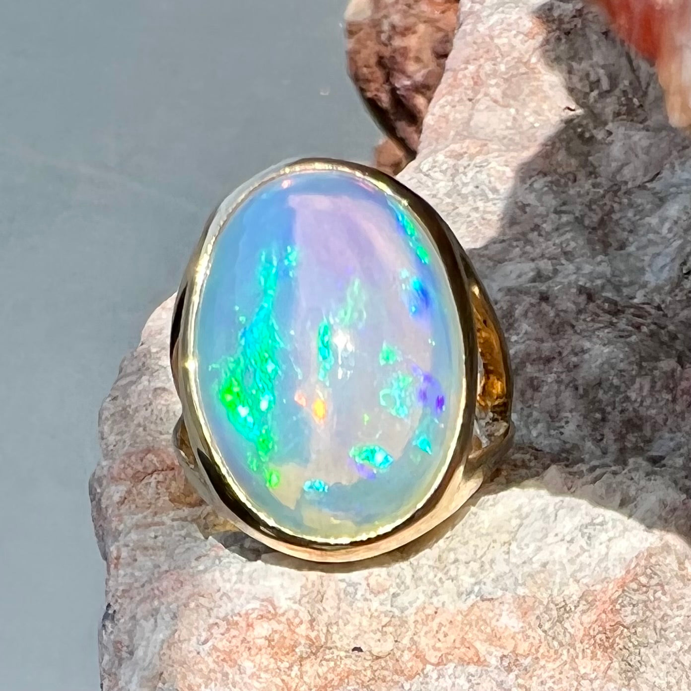 A gold split shank solitaire ring set with an oval cabochon cut 16.83 carat Ethiopian jelly fire opal.
