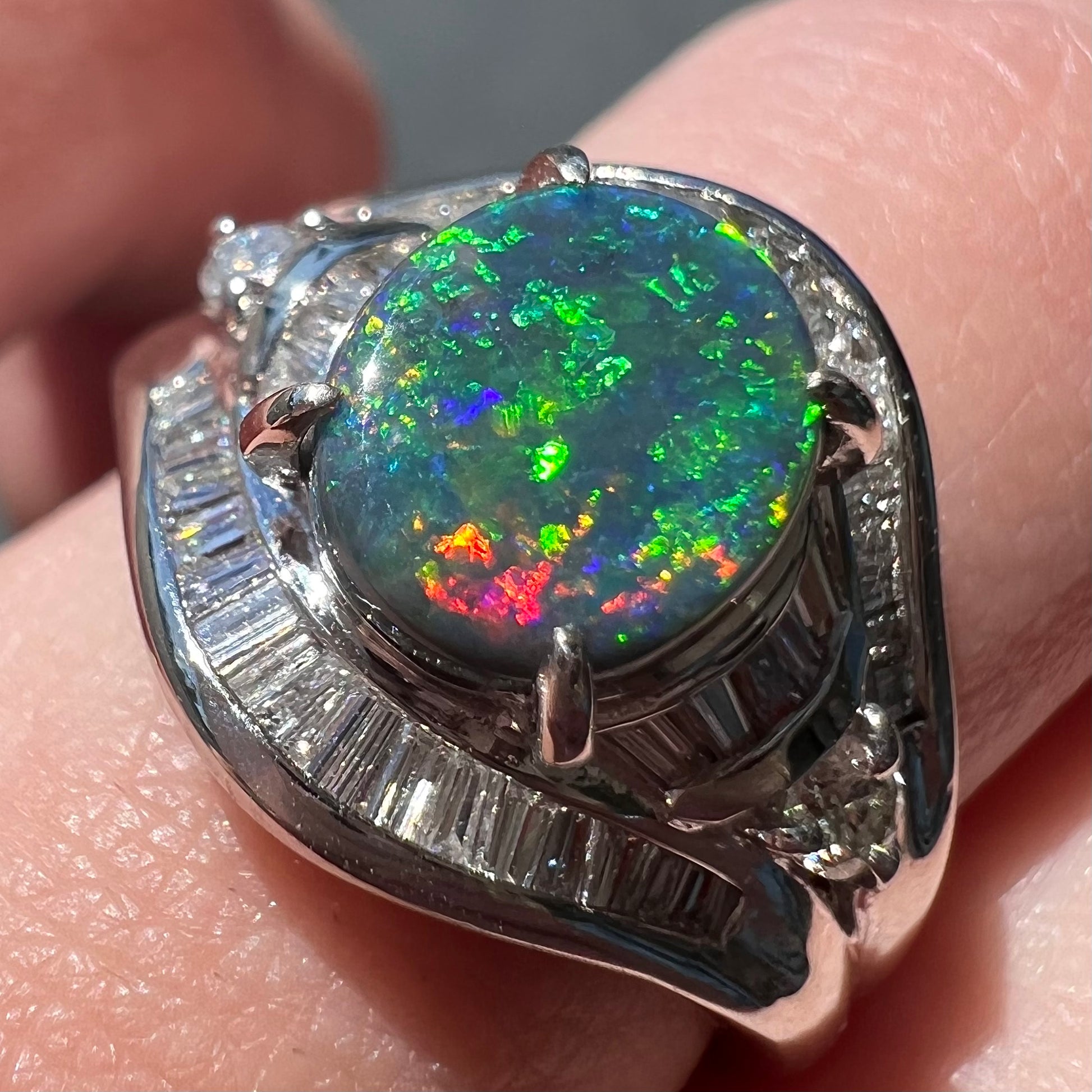 A platinum Lightning Ridge black opal ring set with baguette cut diamonds.  The opal is an oval cabochon cut.