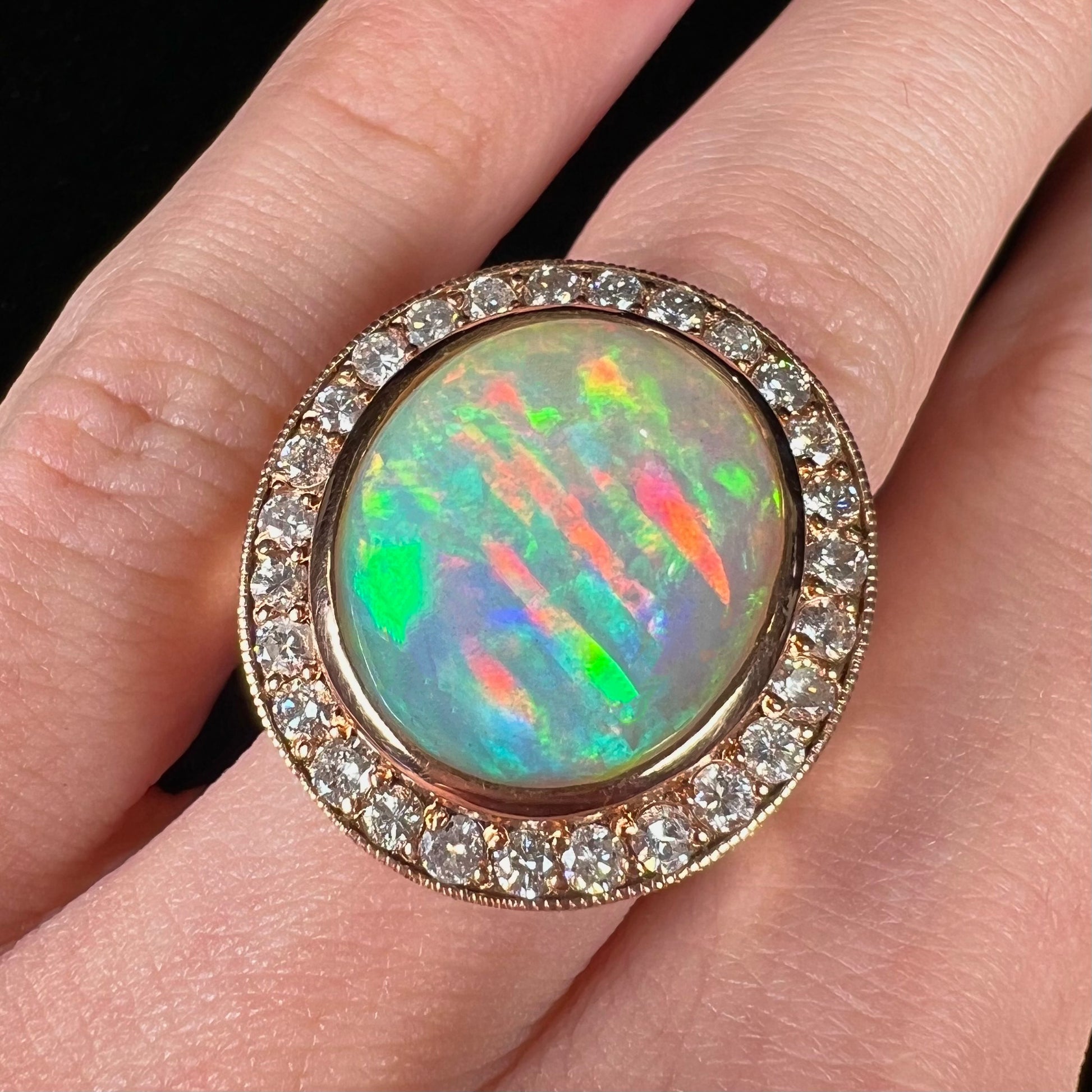 A ladies' natural crystal fire opal ring set in rose gold with a halo of round cut diamonds.