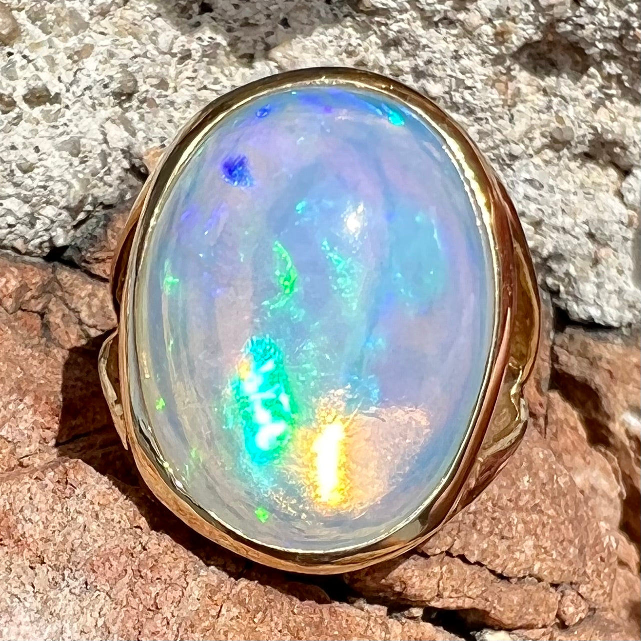 A gold split shank solitaire ring set with an oval cabochon cut 16.83 carat Ethiopian jelly fire opal.
