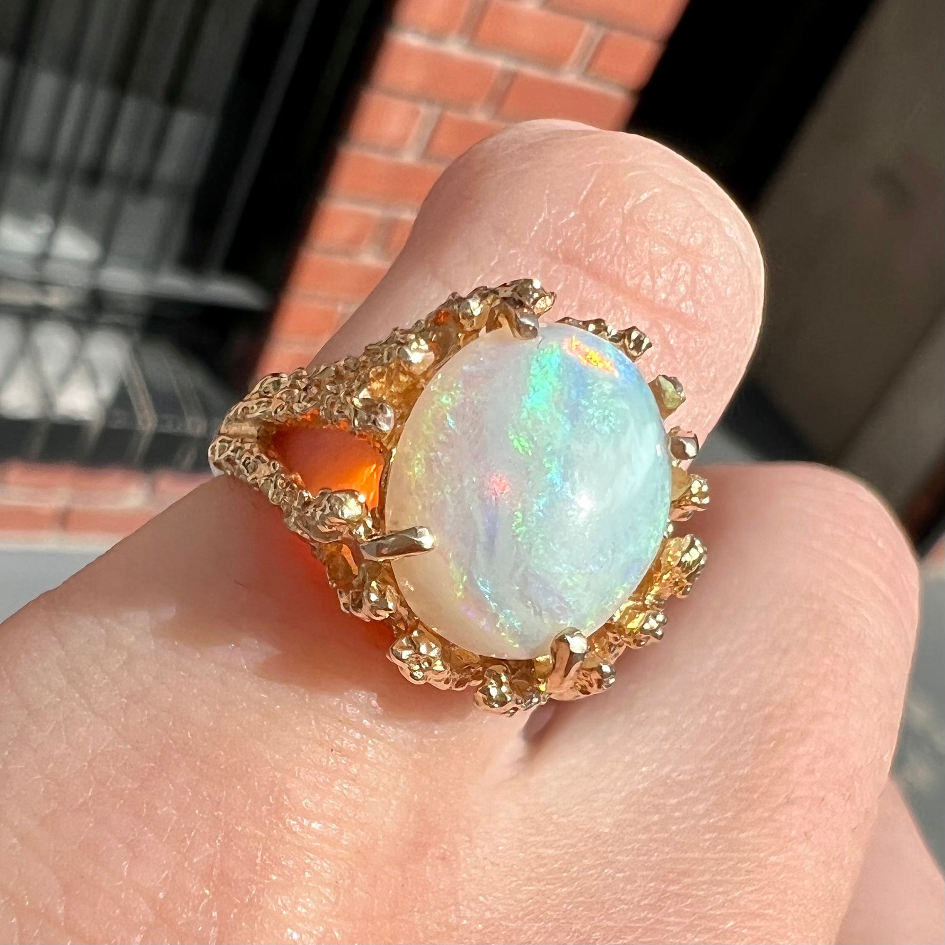 A yellow gold solitaire engagement ring set with an oval cabochon cut white crystal opal.