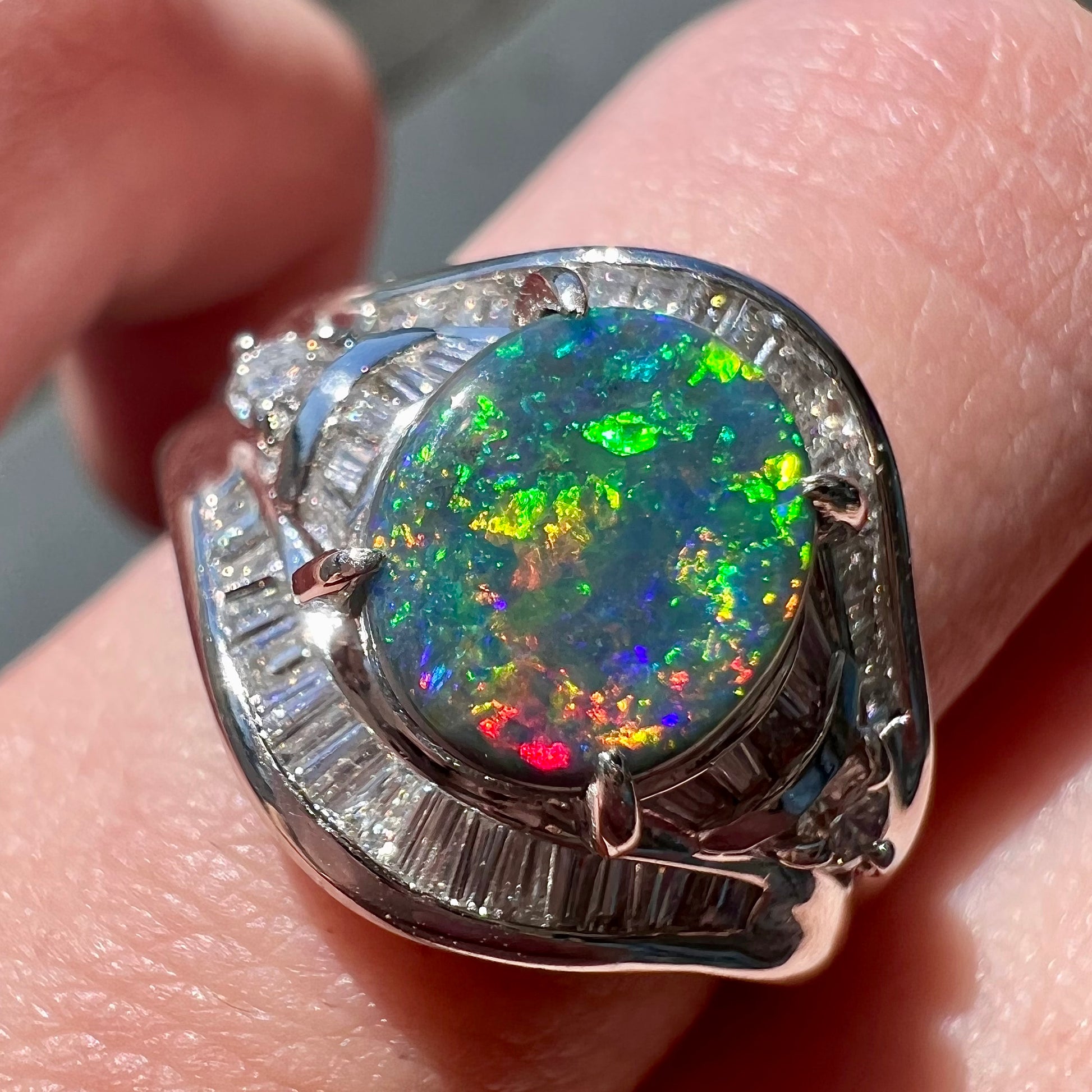 A platinum Lightning Ridge black opal ring set with baguette cut diamonds.  The opal is an oval cabochon cut.