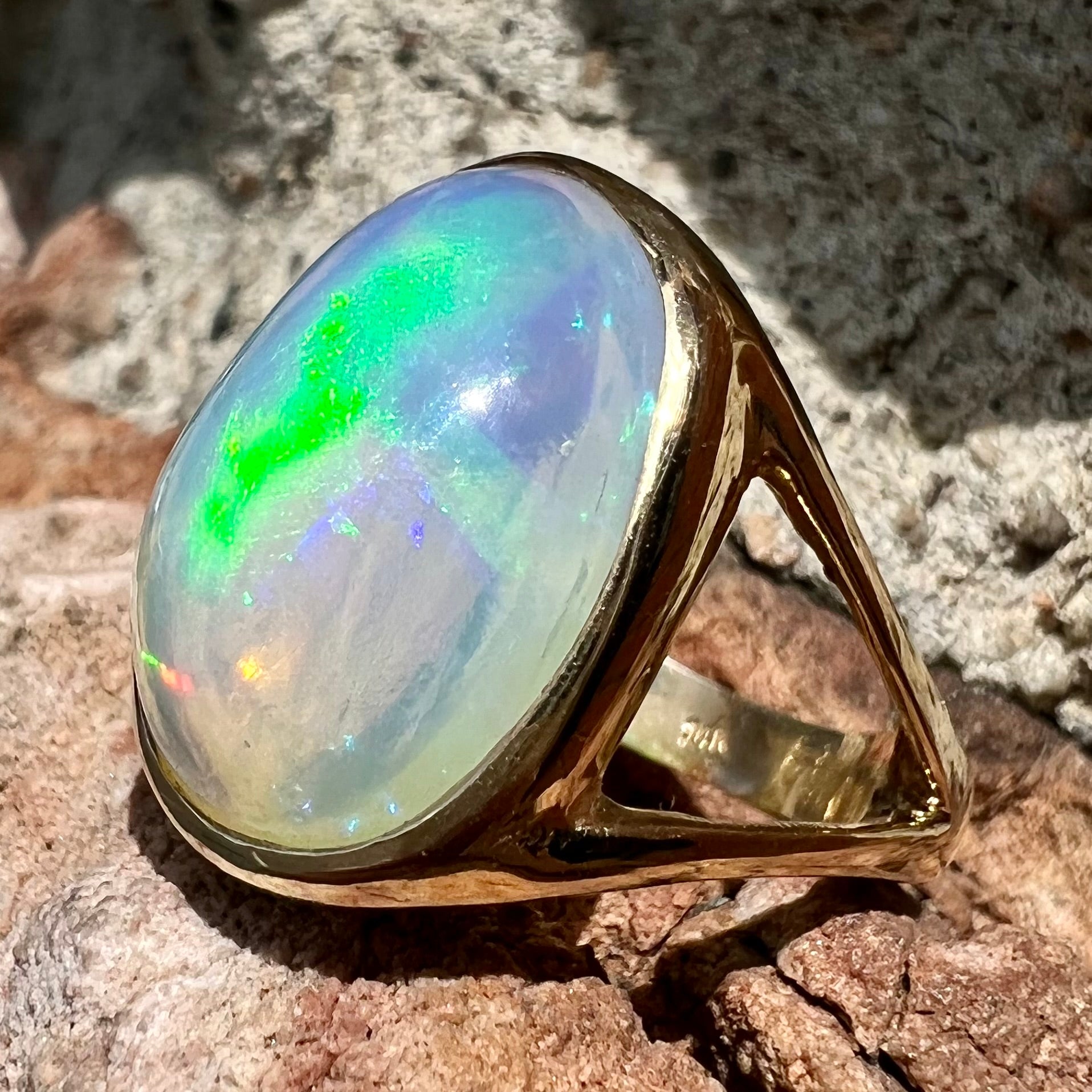 A gold split shank solitaire ring set with an oval cabochon cut 16.83 carat Ethiopian jelly fire opal.