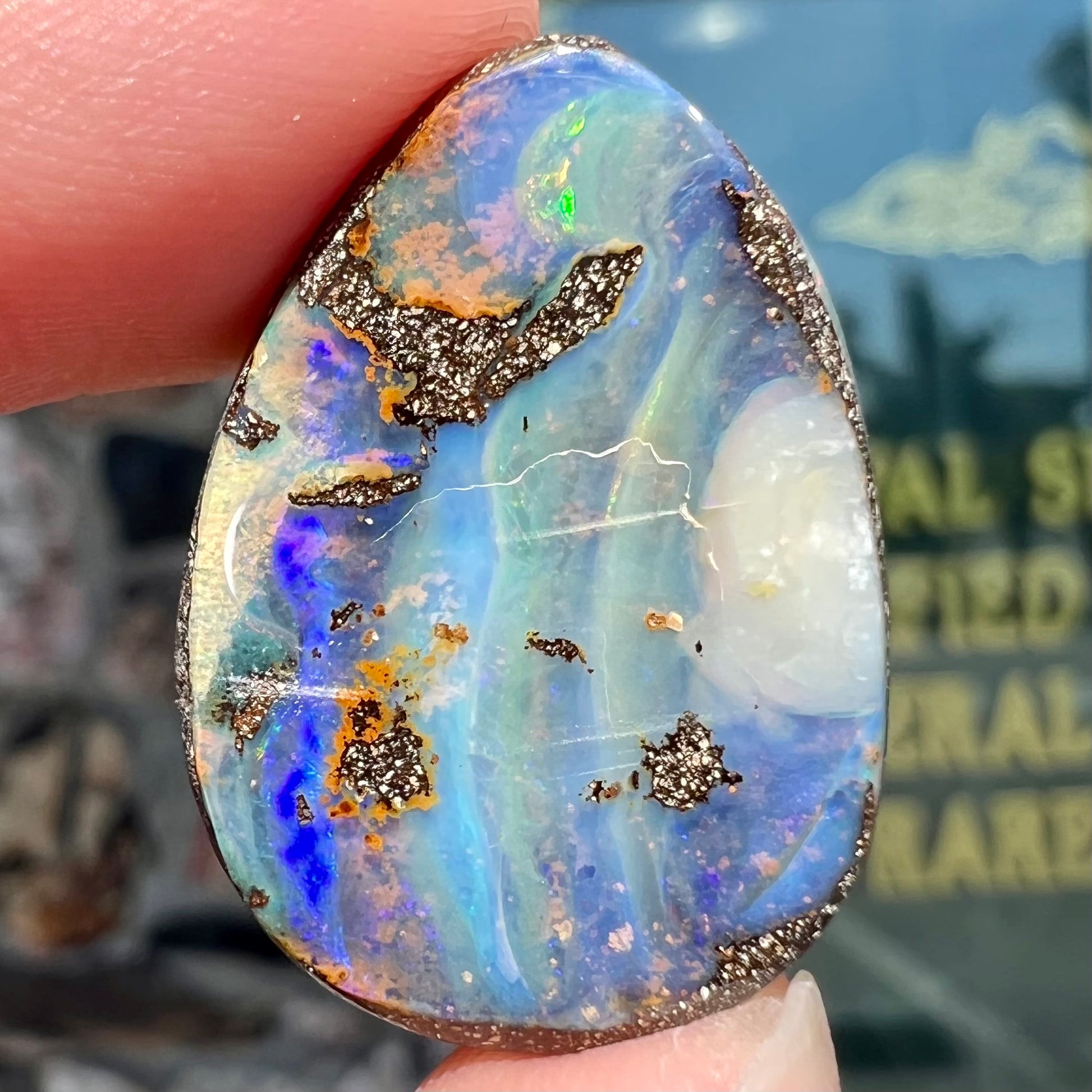 A loose, pear shaped Australian boulder opal.  The pattern on the opal resembles the face of a very sad man.