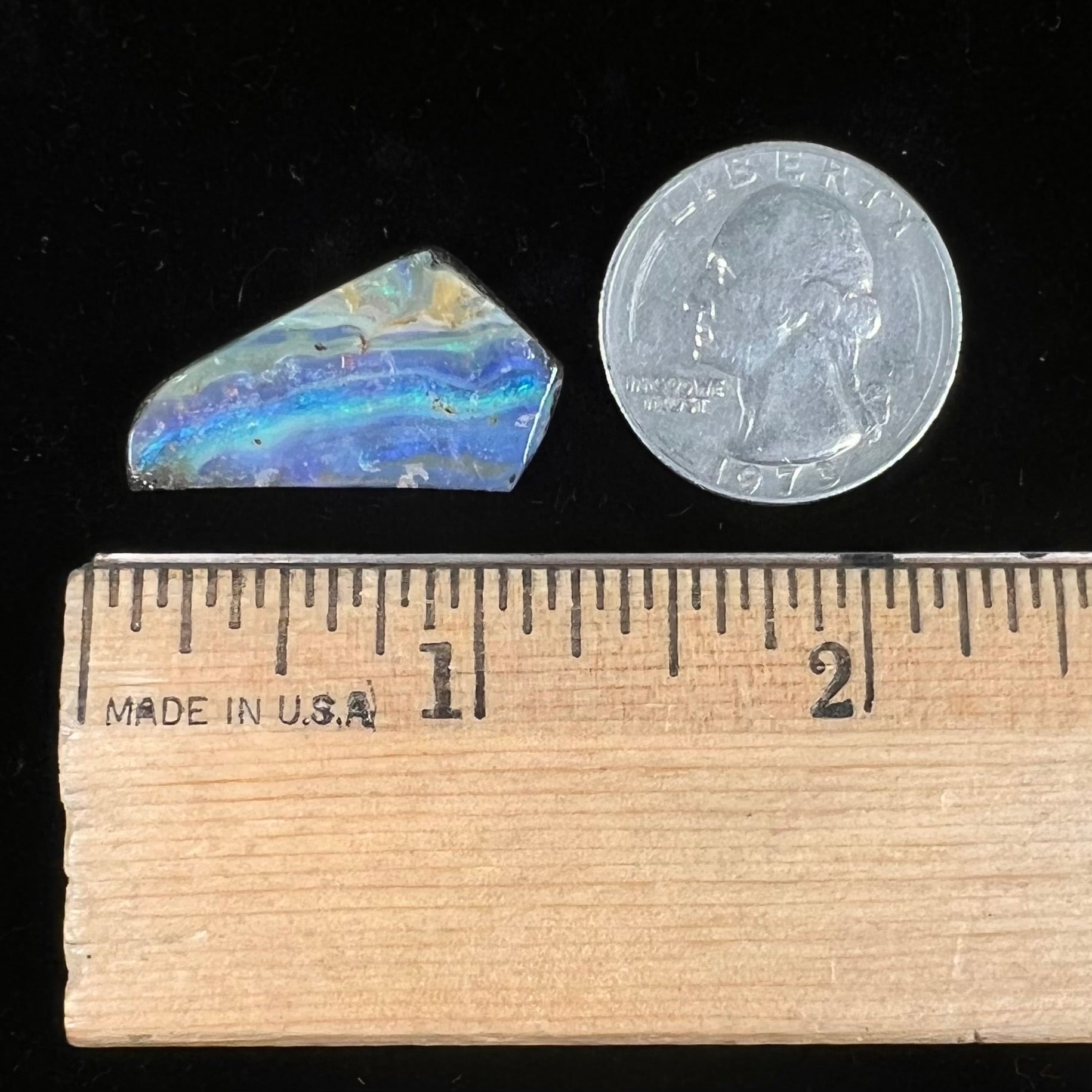 A loose, polished, freeform cut boulder opal stone from Queensland, Australia.