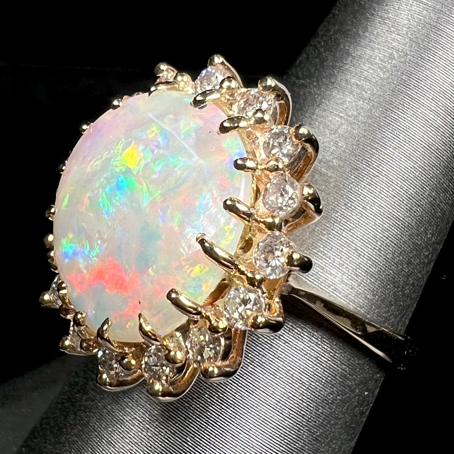 A ladies' diamond halo ring set with a Coober Pedy opalized seashell in yellow gold.