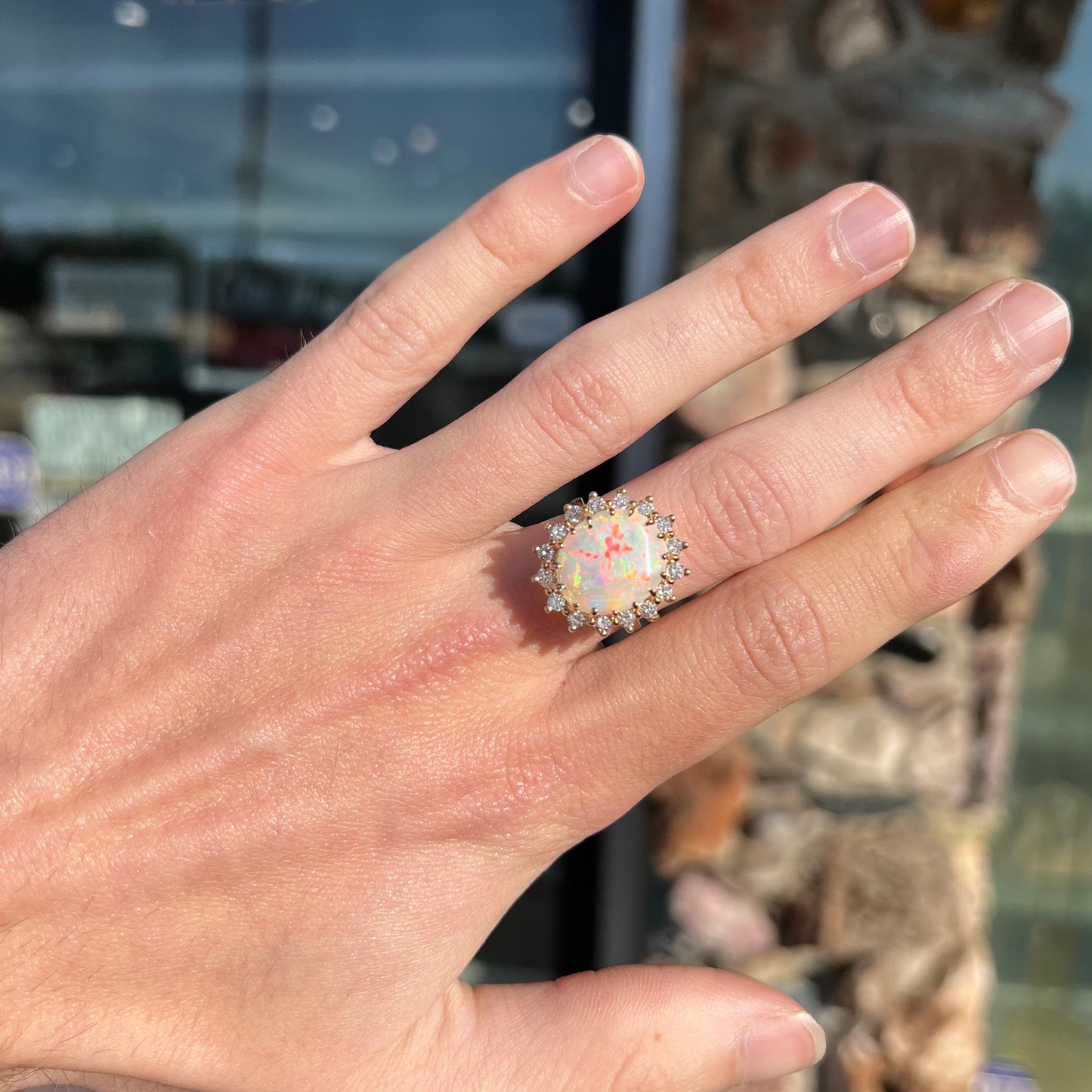 A ladies' diamond halo ring set with a Coober Pedy opalized seashell in yellow gold.