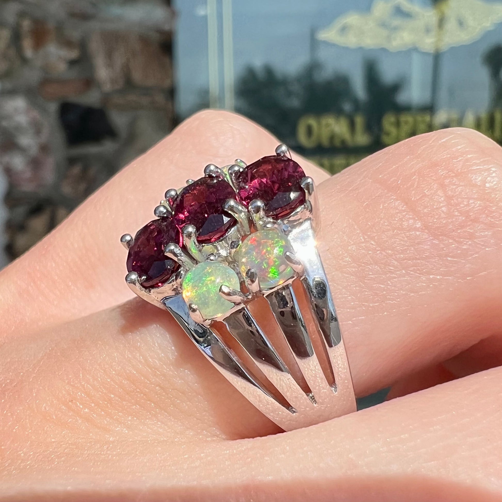 A sterling silver ring set with three oval cut rhodolite garnets and four round cabochon cut Ethiopian opals.