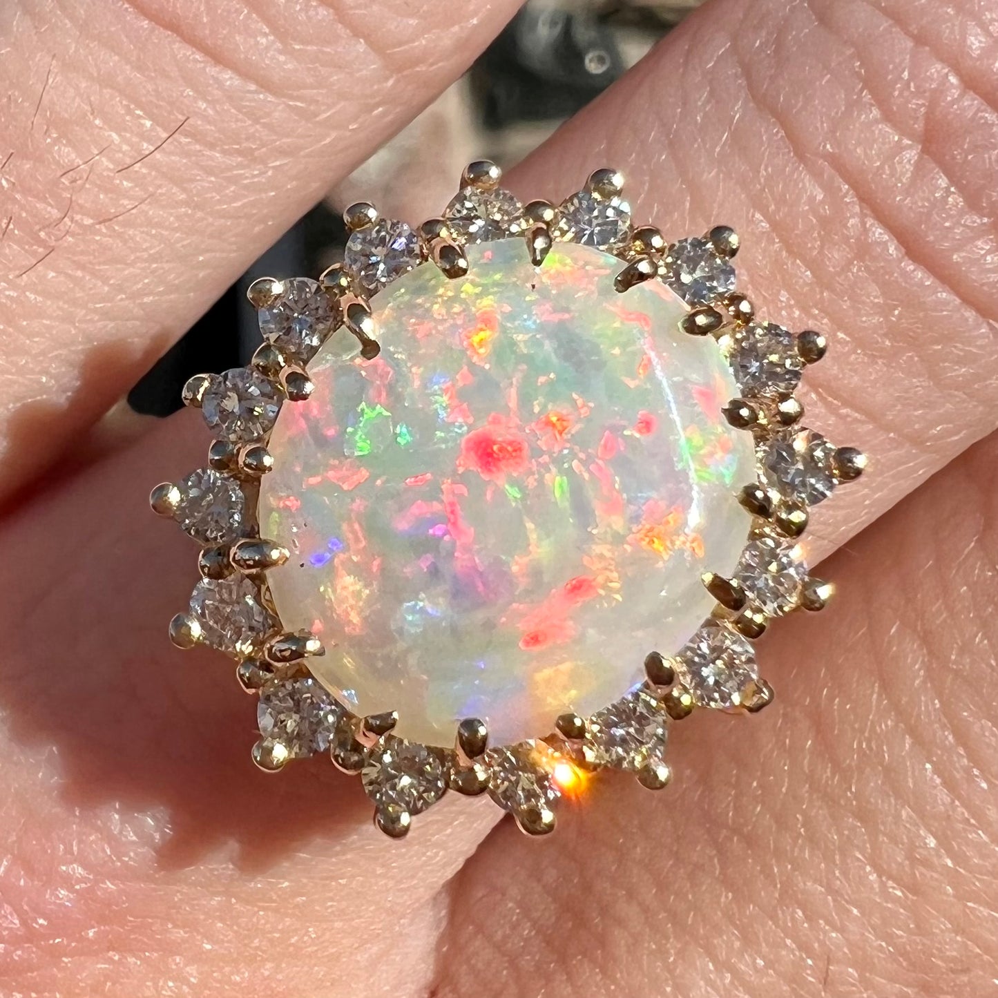 A ladies' diamond halo ring set with a Coober Pedy opalized seashell in yellow gold.