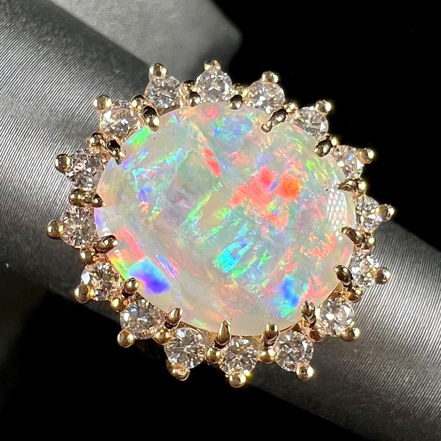 A ladies' diamond halo ring set with a Coober Pedy opalized seashell in yellow gold.