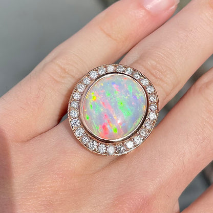 A large, Australian white crystal opal set in a rose gold and diamond halo ring.