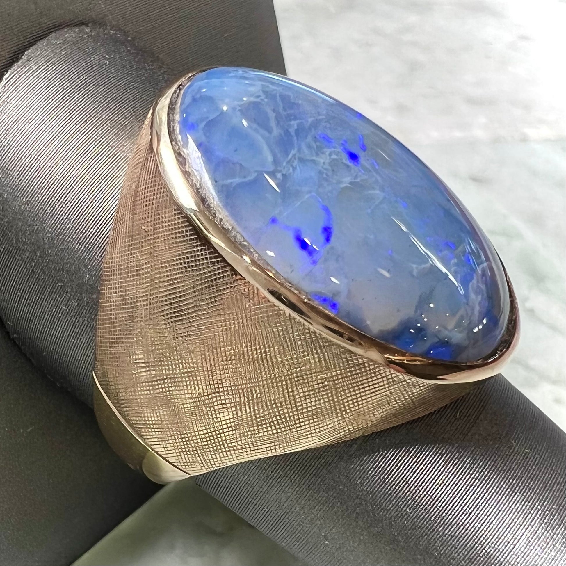 A Lightning Ridge black opal men's ring in solid yellow textured gold.