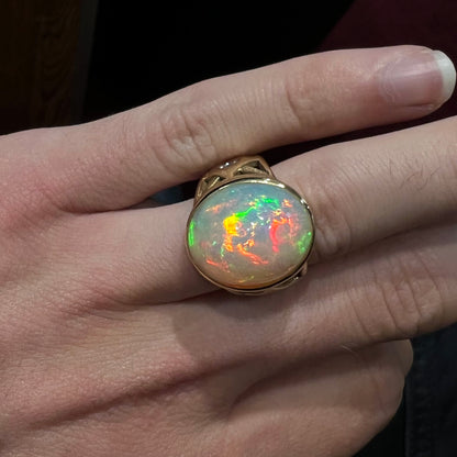 A custom yellow gold men's ring set with two diamonds and a large oval cabochon cut opal from Ethiopia, Africa.