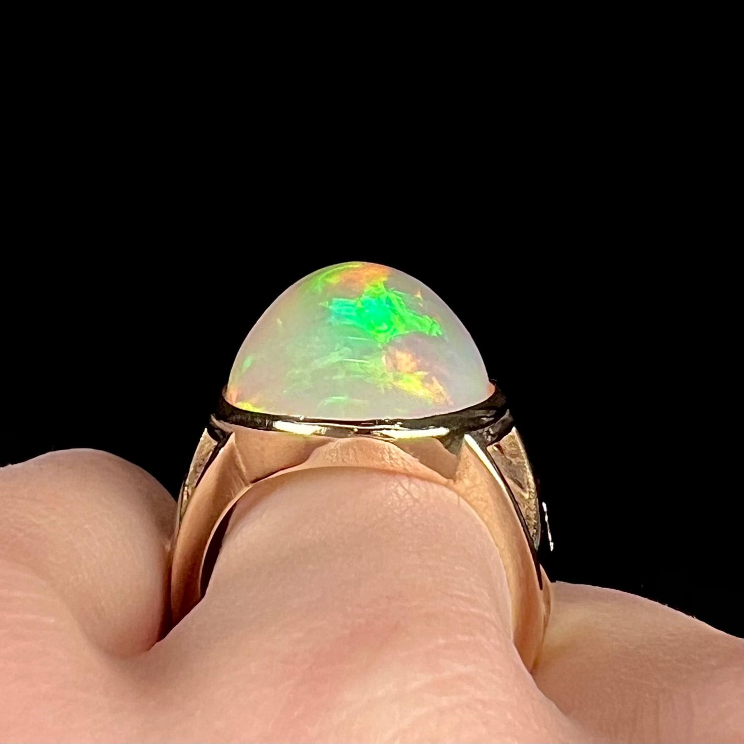 A custom yellow gold men's ring set with two diamonds and a large oval cabochon cut opal from Ethiopia, Africa.