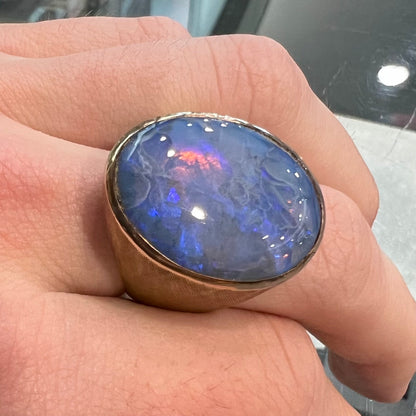 A Lightning Ridge black opal men's ring in solid yellow textured gold.