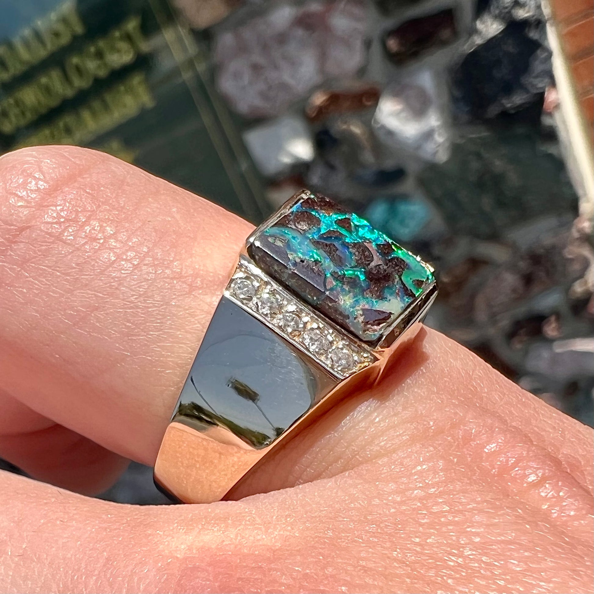A men's gold boulder opal and diamond ring.  The opal shows blue and green colors.