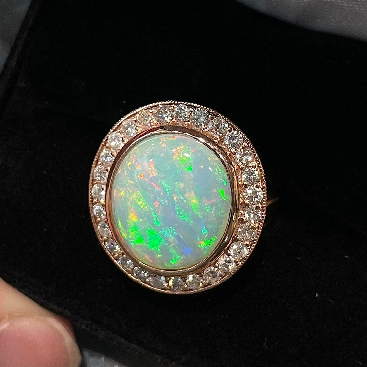 A large, Australian white crystal opal set in a rose gold and diamond halo ring.