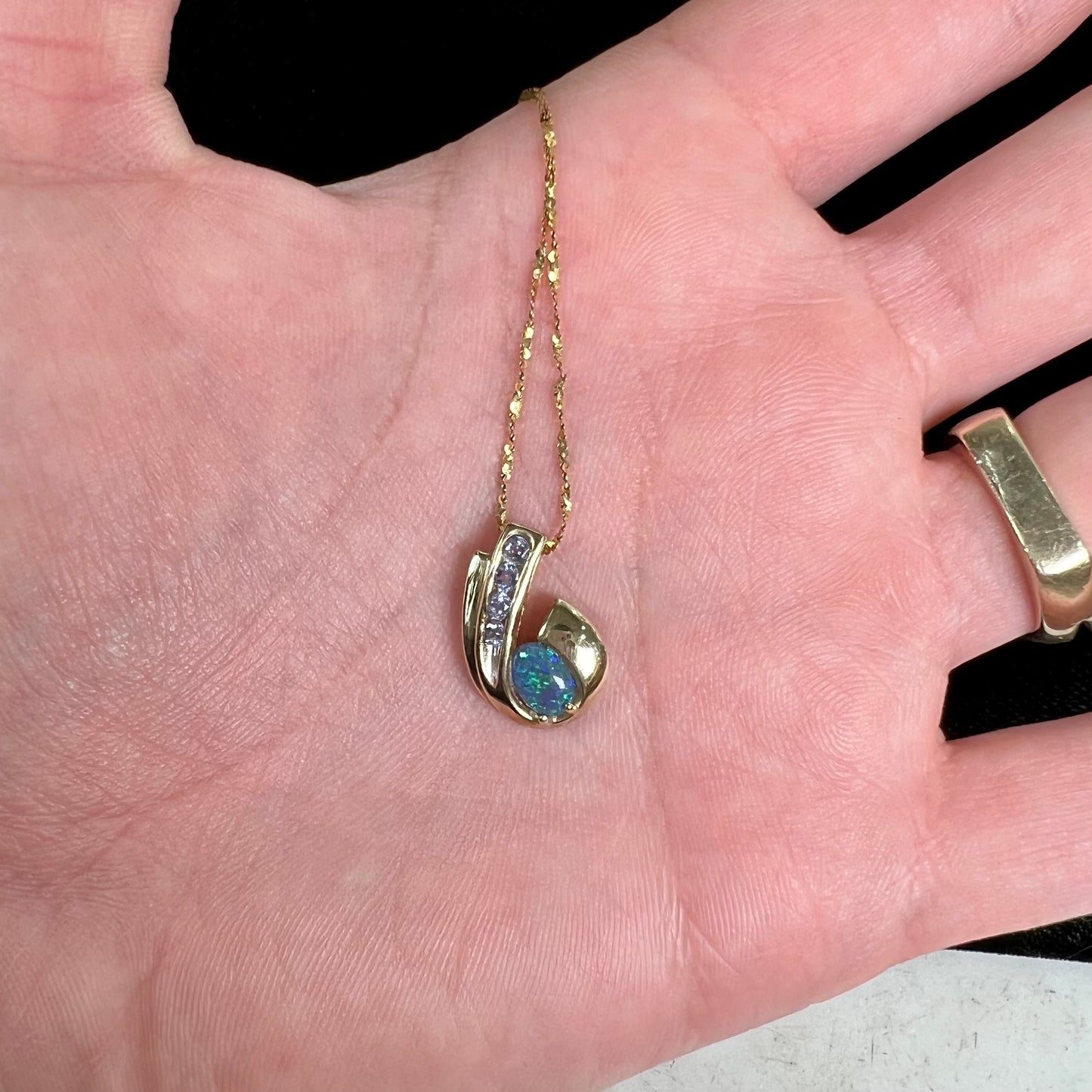 A Lightning Ridge black crystal opal necklace set with blue tanzanite in yellow gold.  Gold chain not included.