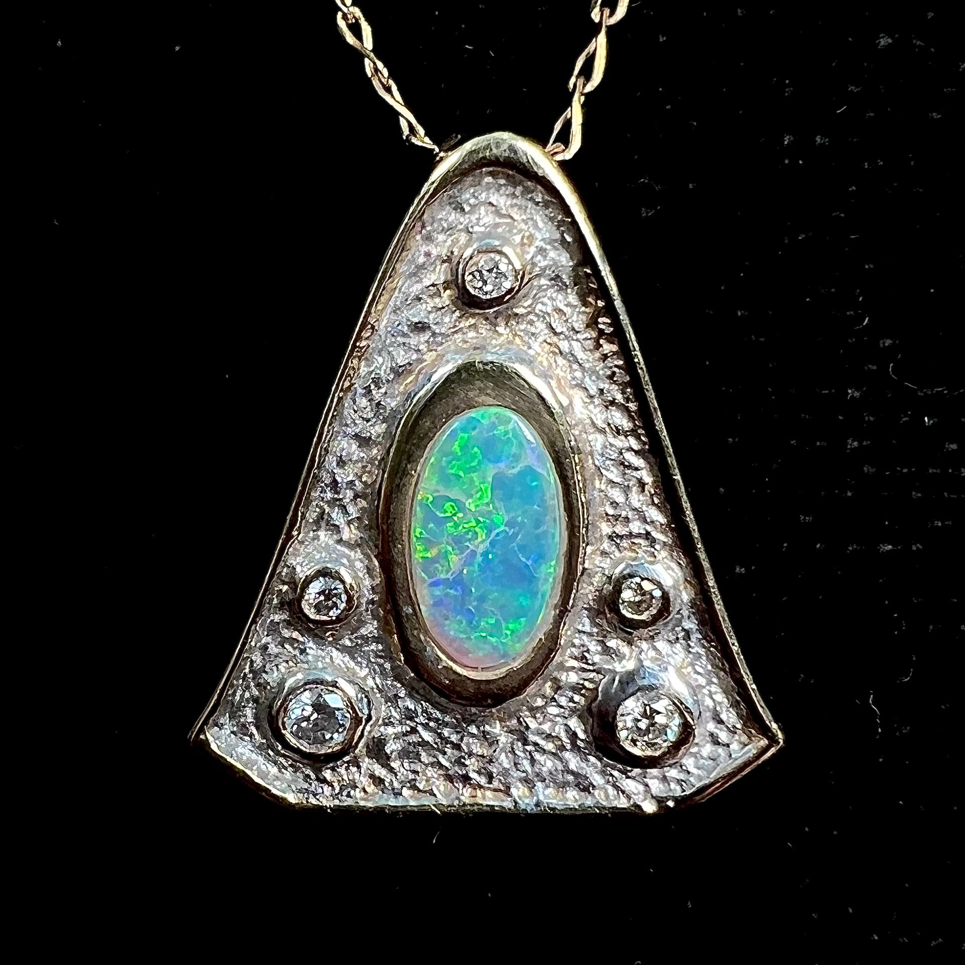 A triangular gold pendant set with five round diamonds and a white crystal opal with green fire.