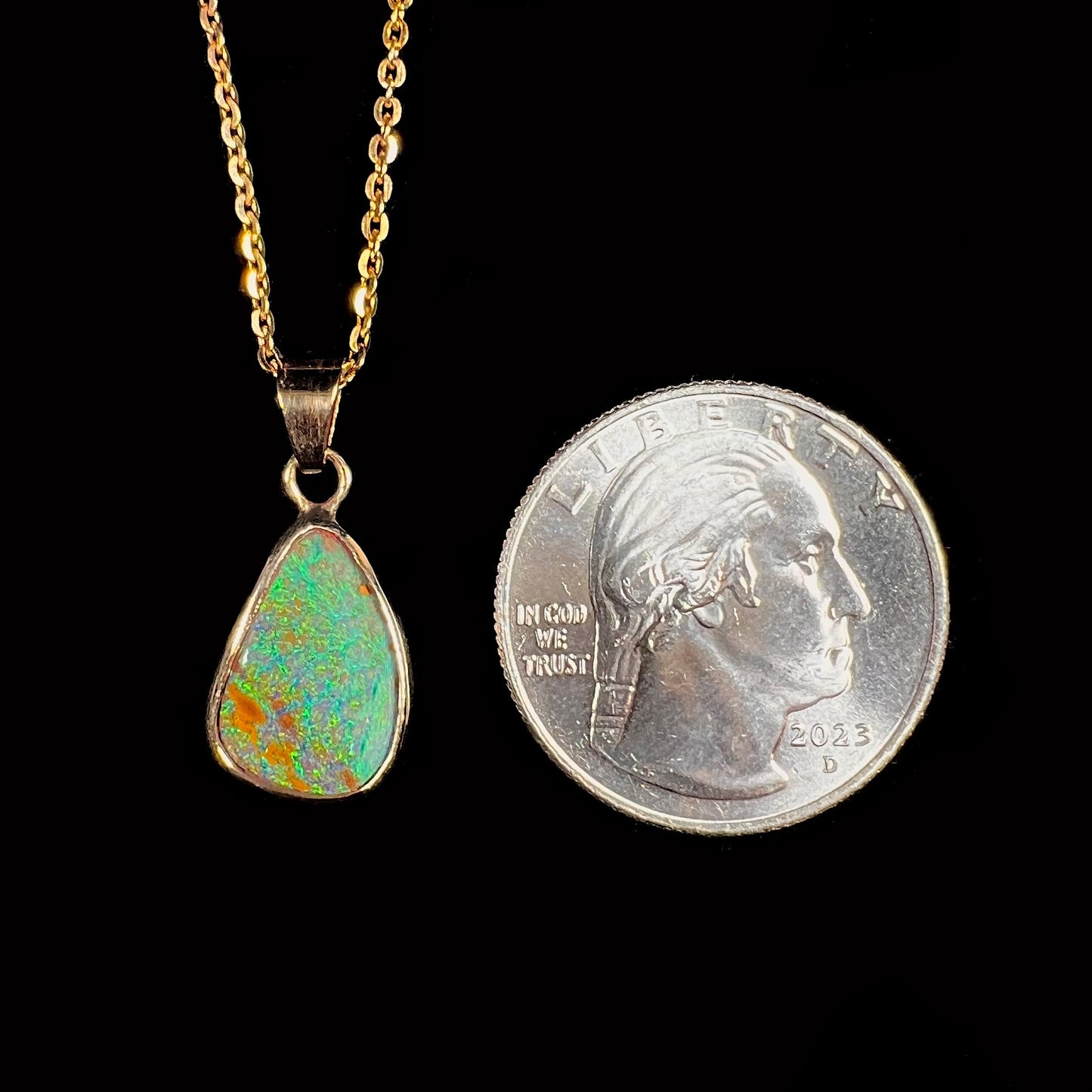 A ladies' natural boulder opal necklace set in 14k yellow gold.  The opal is bezel set and shows green and blue colors.