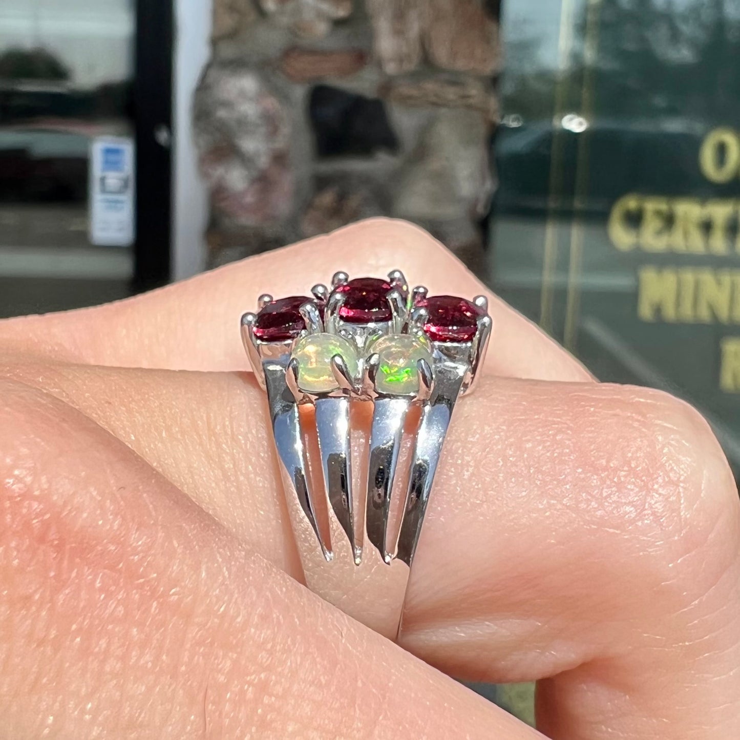 A sterling silver ring set with three oval cut rhodolite garnets and four round cabochon cut Ethiopian opals.