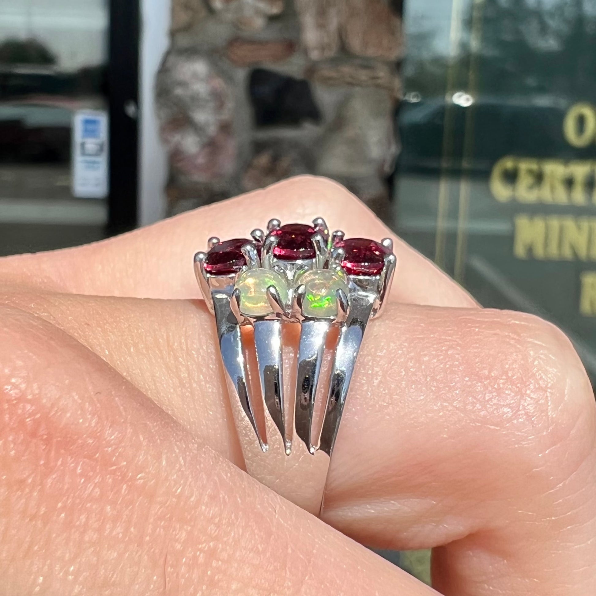 A sterling silver ring set with three oval cut rhodolite garnets and four round cabochon cut Ethiopian opals.