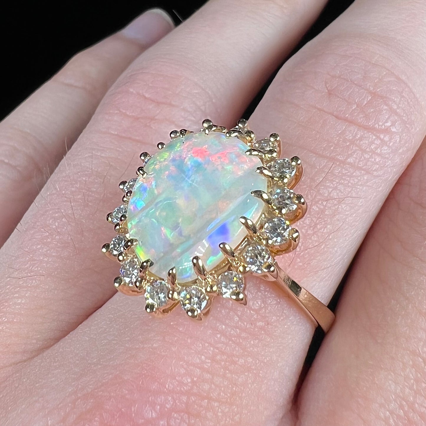 A ladies' diamond halo ring set with a Coober Pedy opalized seashell in yellow gold.