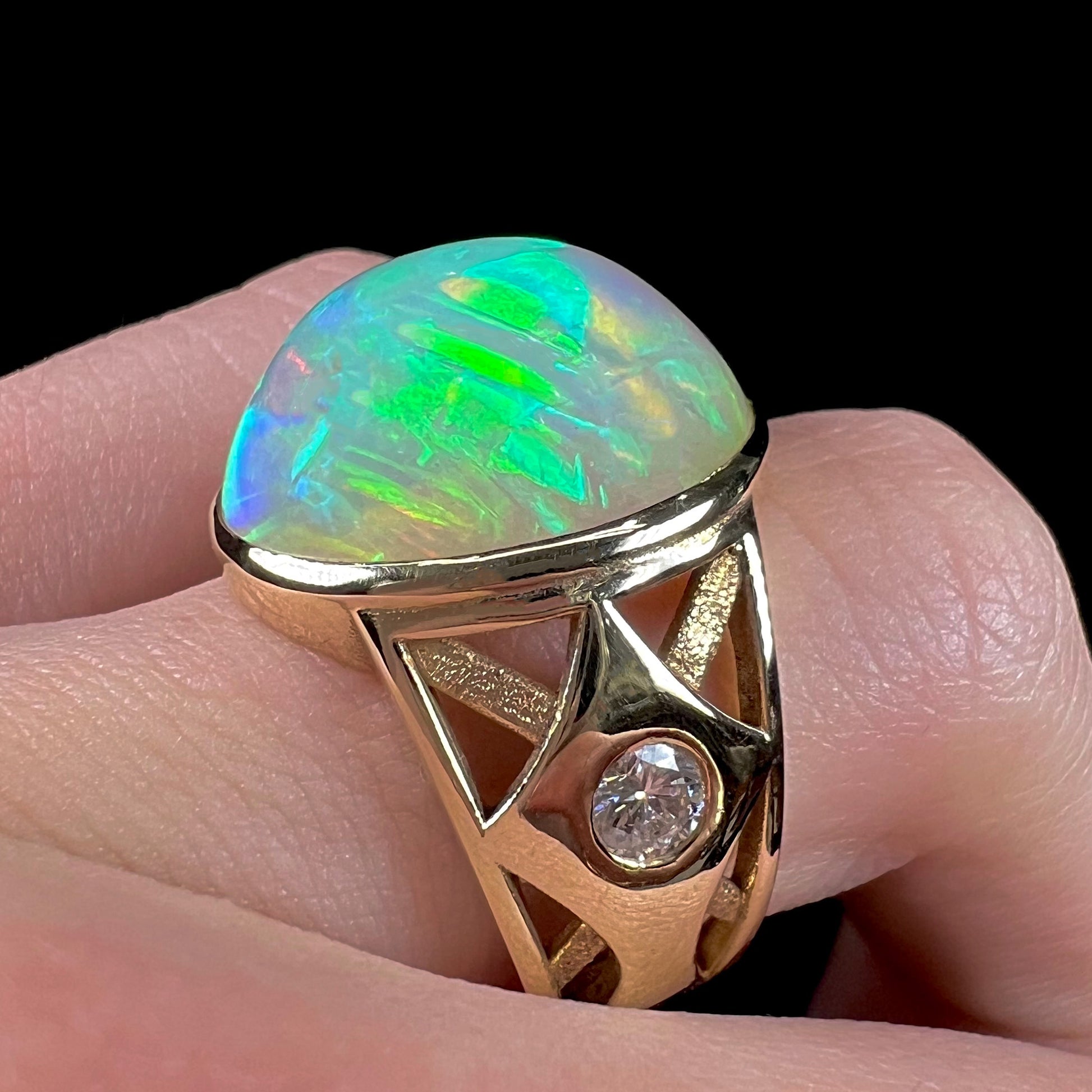 A custom yellow gold men's ring set with two diamonds and a large oval cabochon cut opal from Ethiopia, Africa.