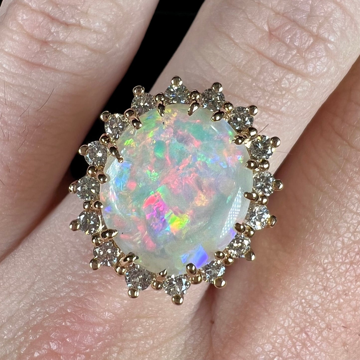 A ladies' diamond halo ring set with a Coober Pedy opalized seashell in yellow gold.