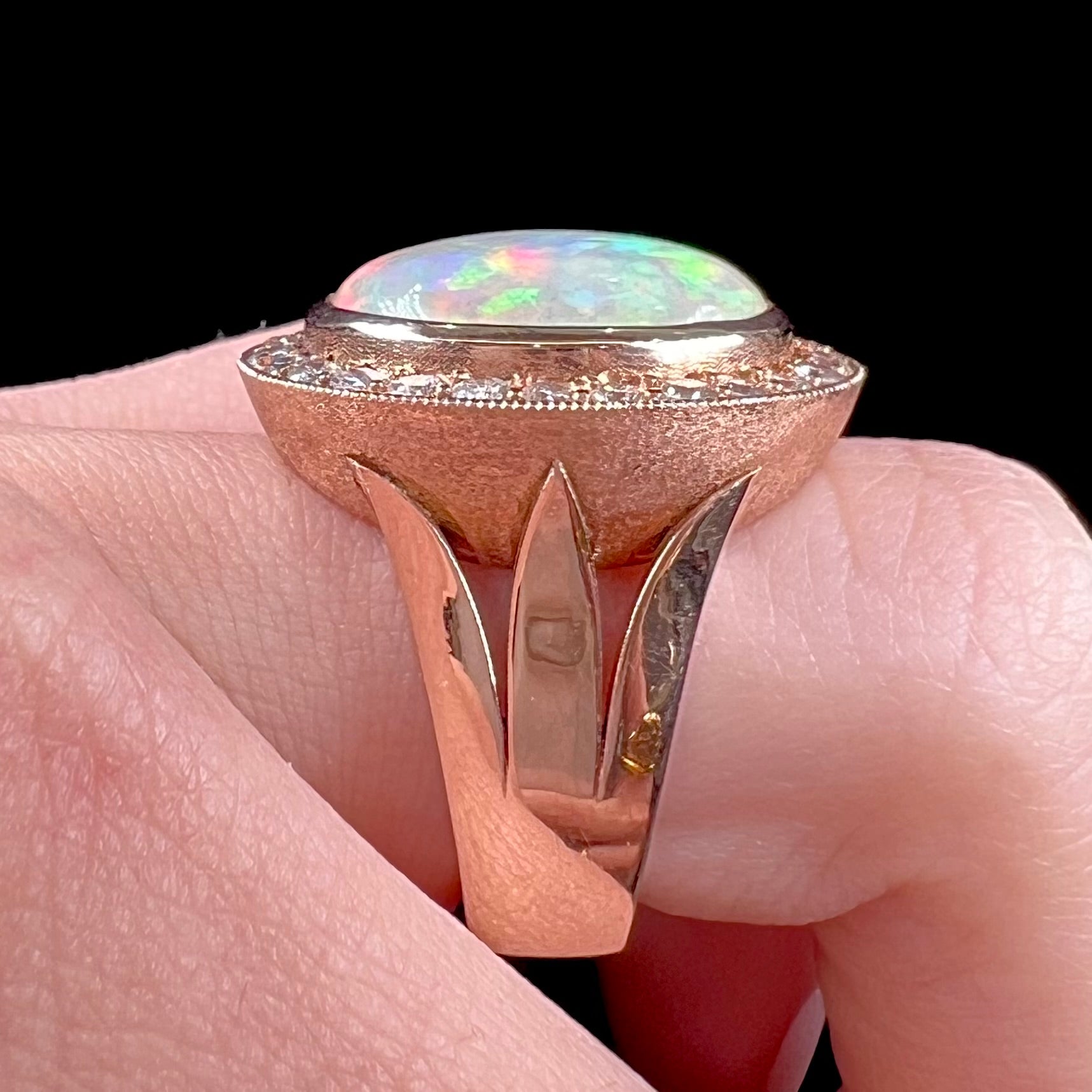 A ladies' natural crystal fire opal ring set in rose gold with a halo of round cut diamonds.