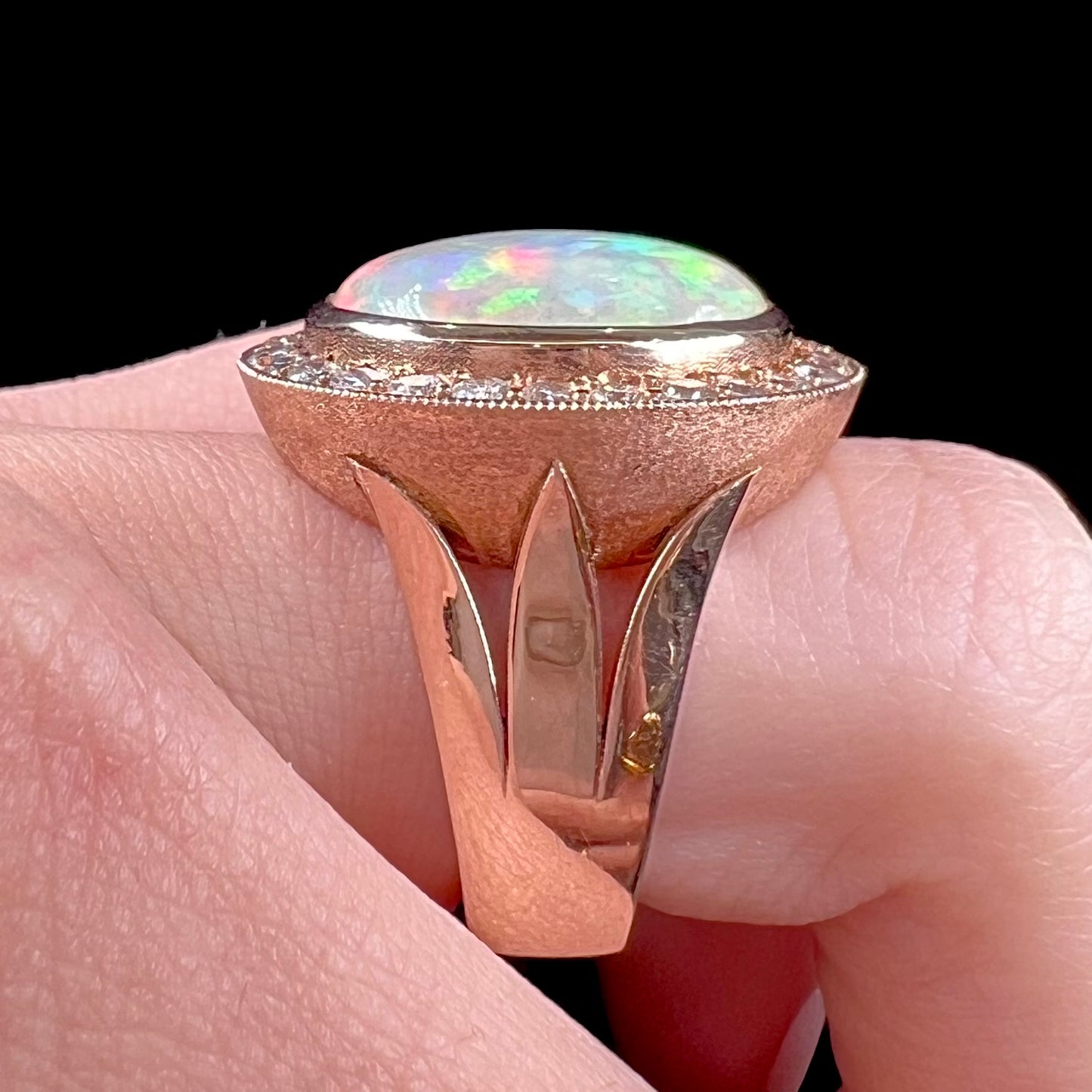 A ladies' natural crystal fire opal ring set in rose gold with a halo of round cut diamonds.