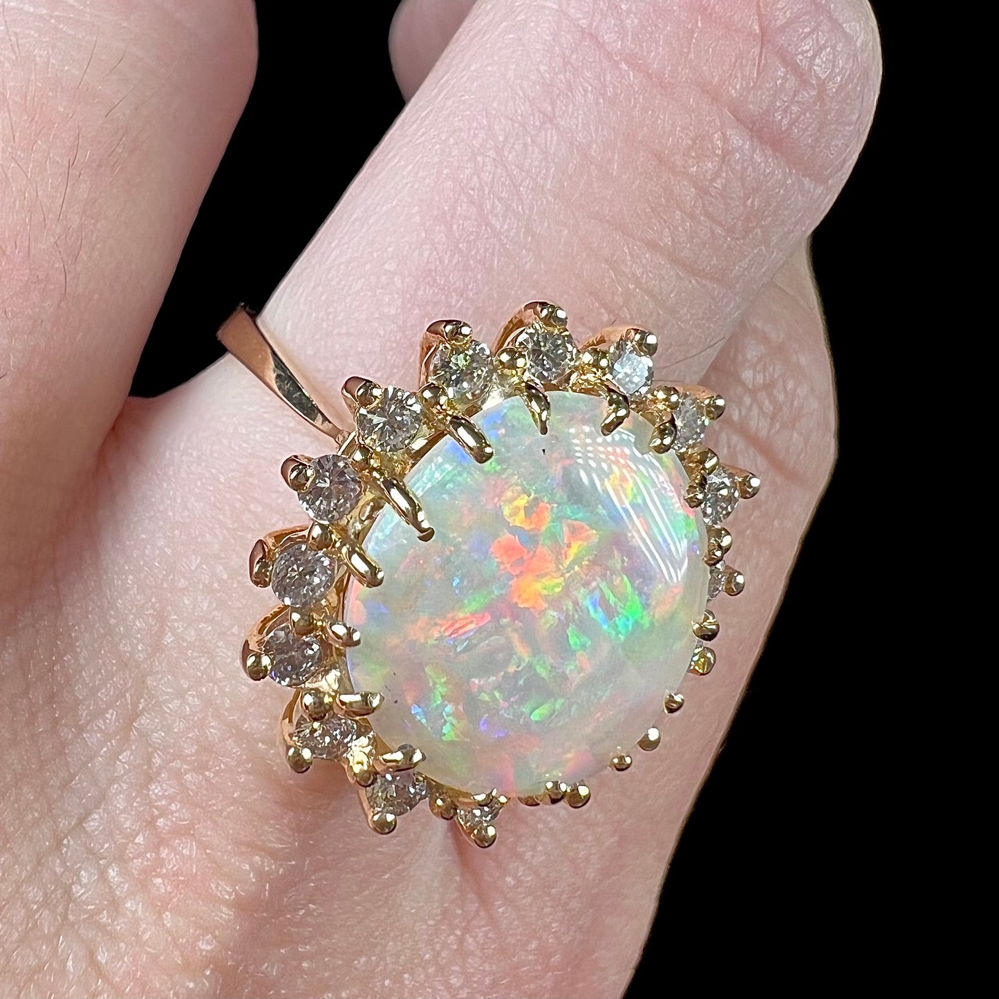 A ladies' diamond halo ring set with a Coober Pedy opalized seashell in yellow gold.