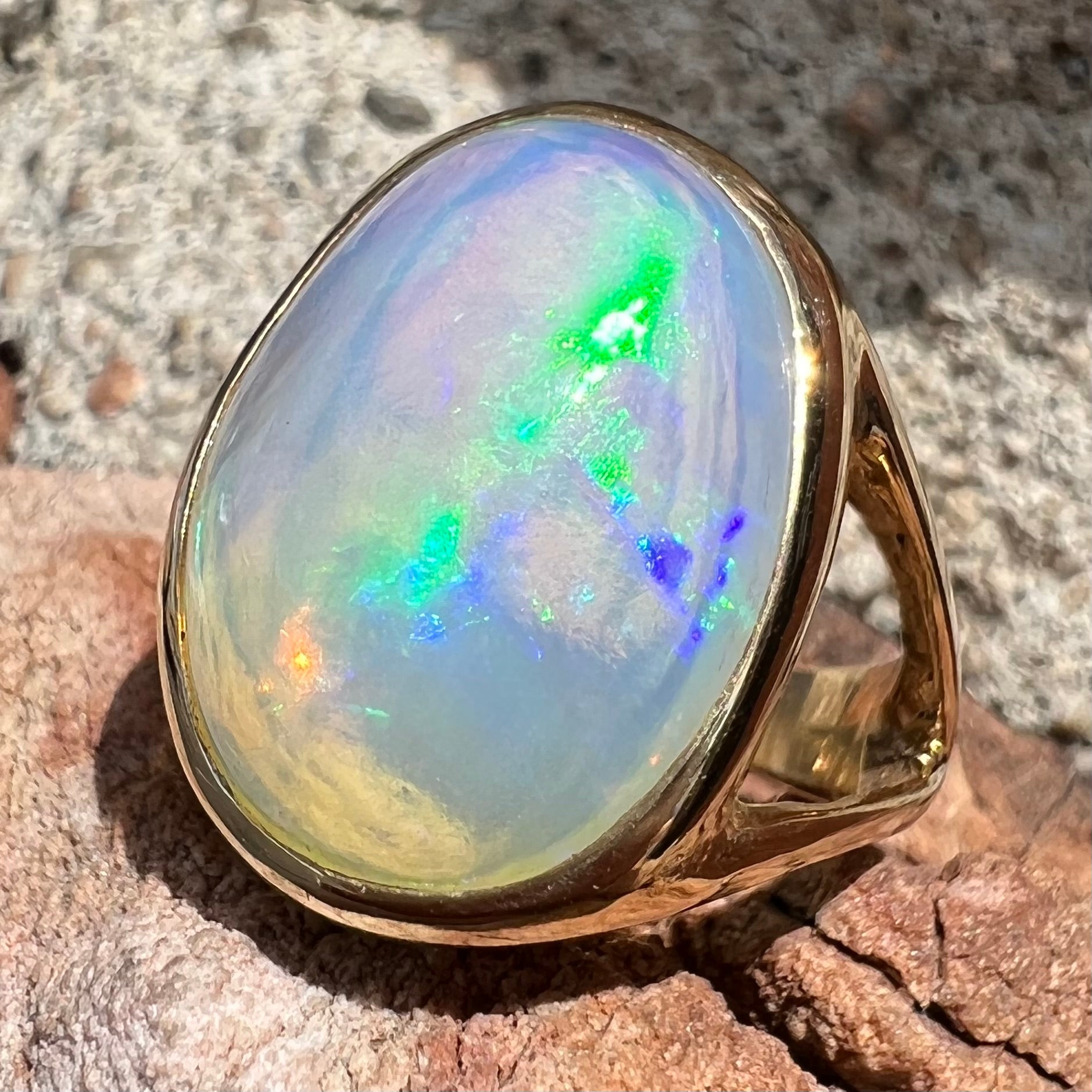 A gold split shank solitaire ring set with an oval cabochon cut 16.83 carat Ethiopian jelly fire opal.