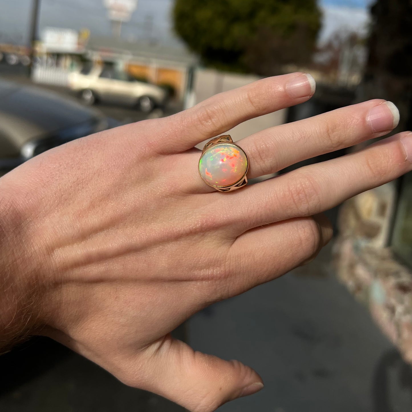 A custom yellow gold men's ring set with two diamonds and a large oval cabochon cut opal from Ethiopia, Africa.