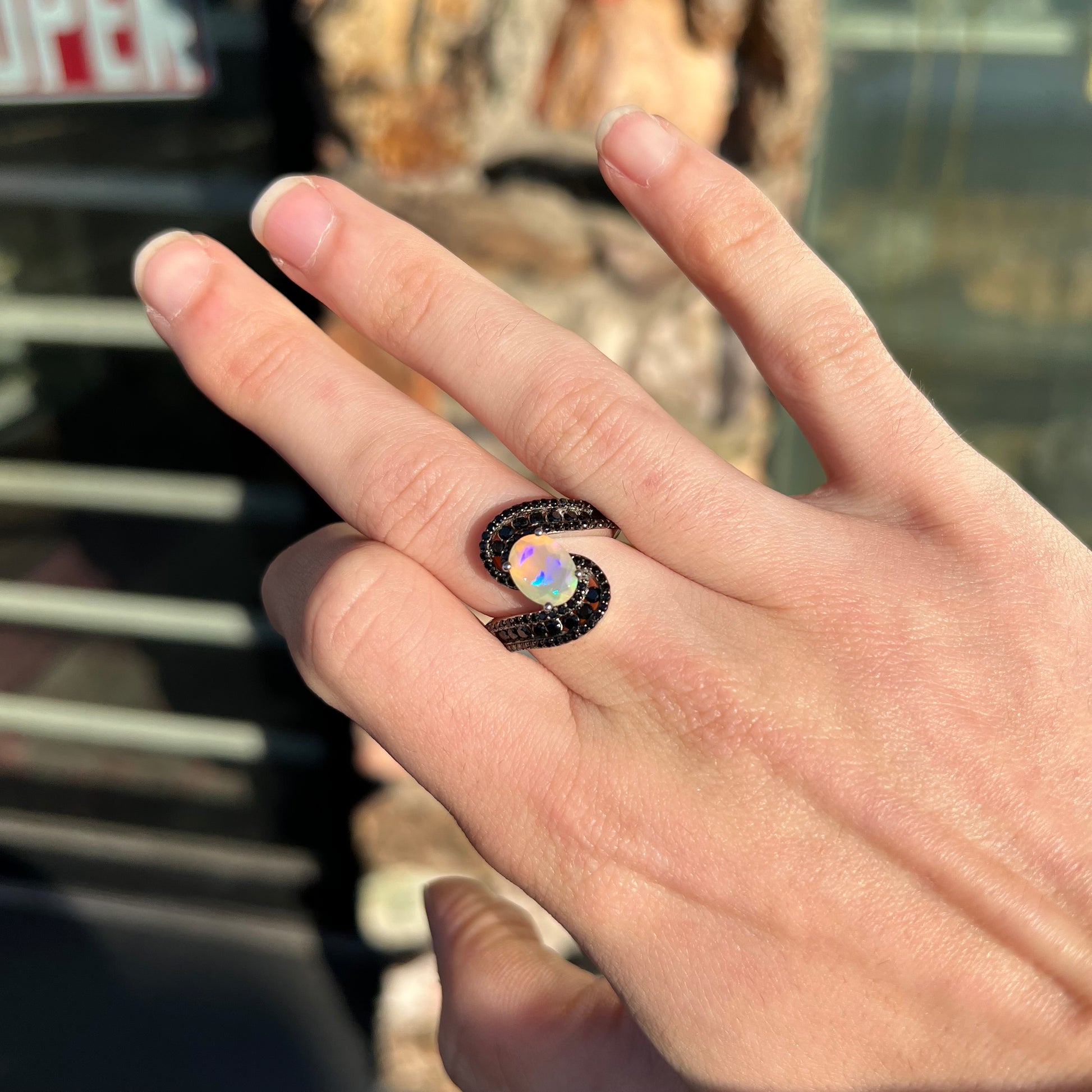 A sterling silver ring set with round black spinel stones and an oval cut, faceted Ethiopian opal.