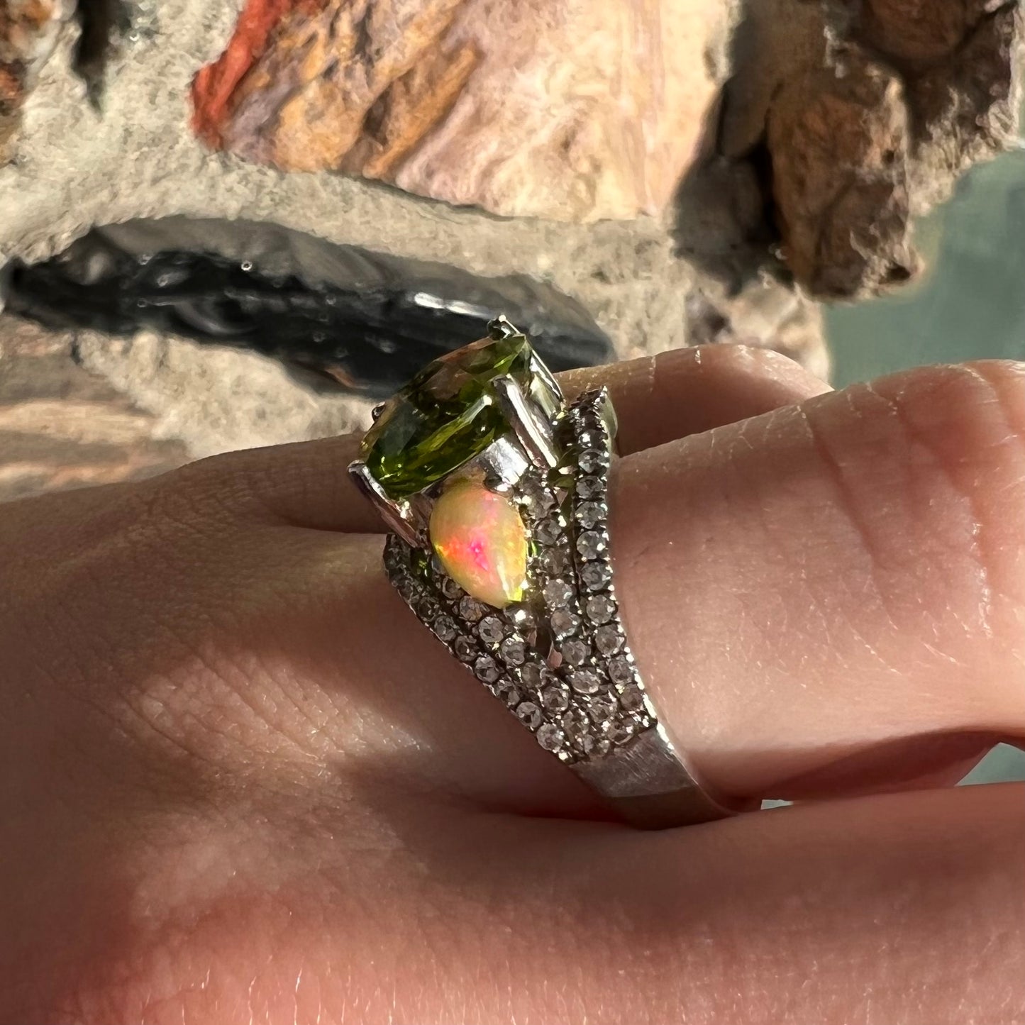 A sterling silver ring set with one large round peridot stone set between two pear shape cabochon Ethiopian opals.  Cubic zirconia stones line the ring.