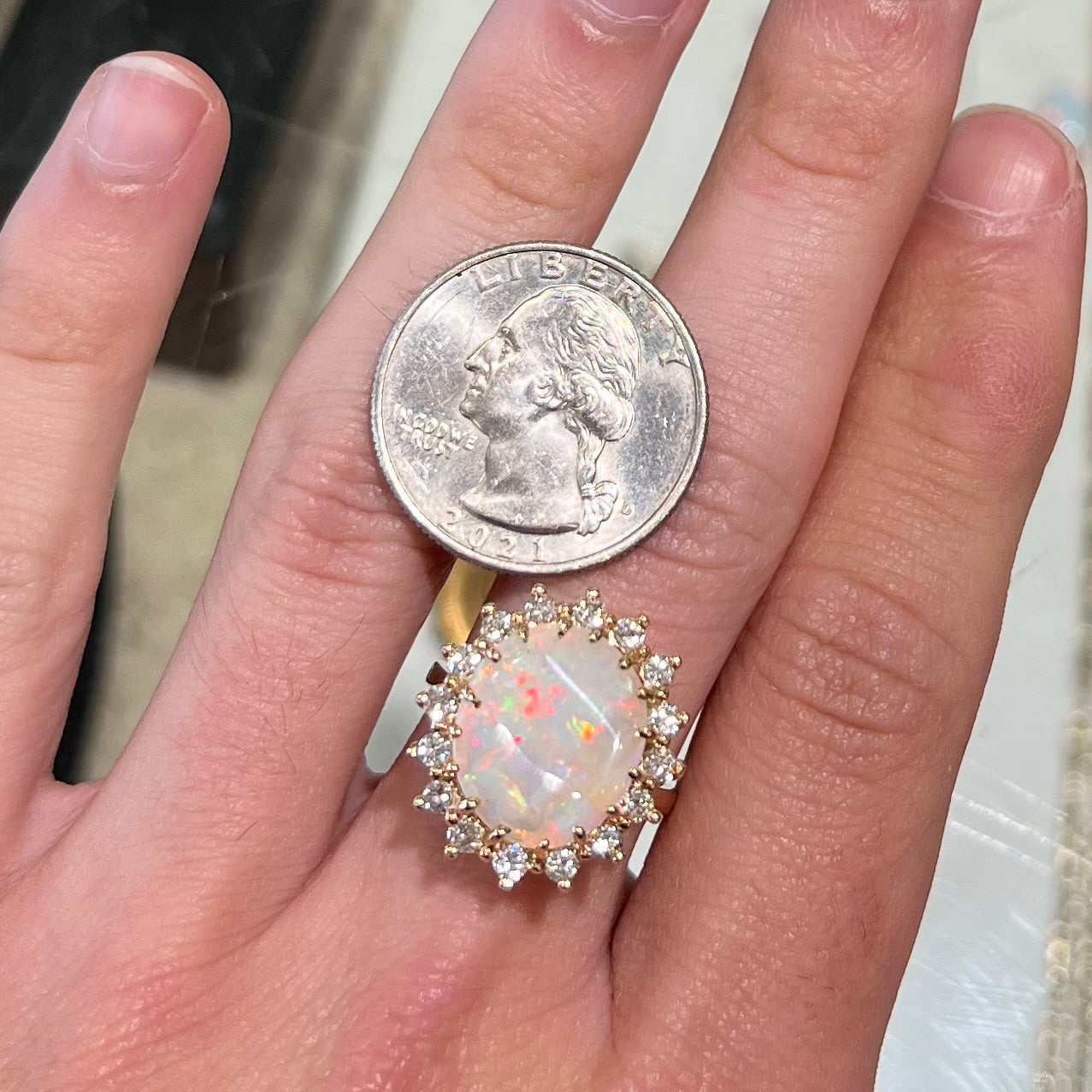 A ladies' diamond halo ring set with a Coober Pedy opalized seashell in yellow gold.