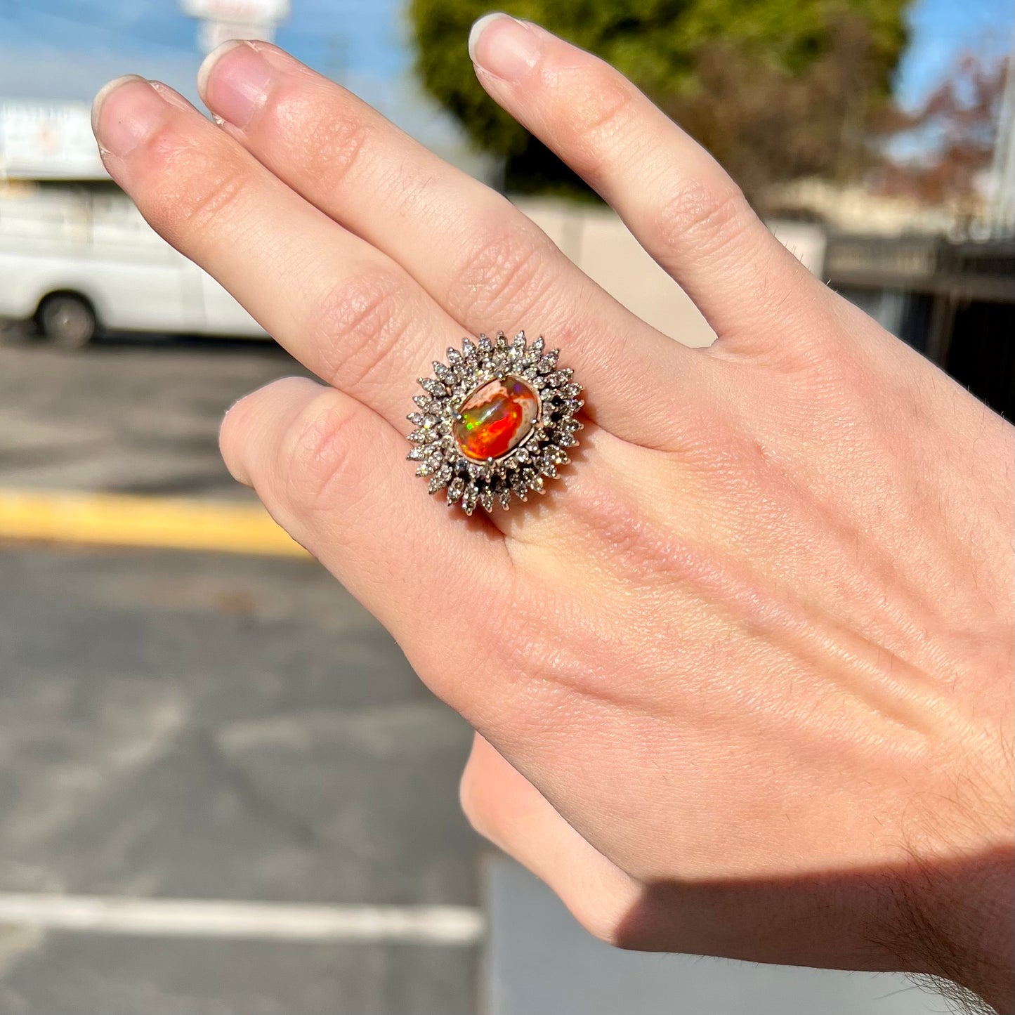 An 18k white gold orange fire opal ring set with a triple halo of diamonds.