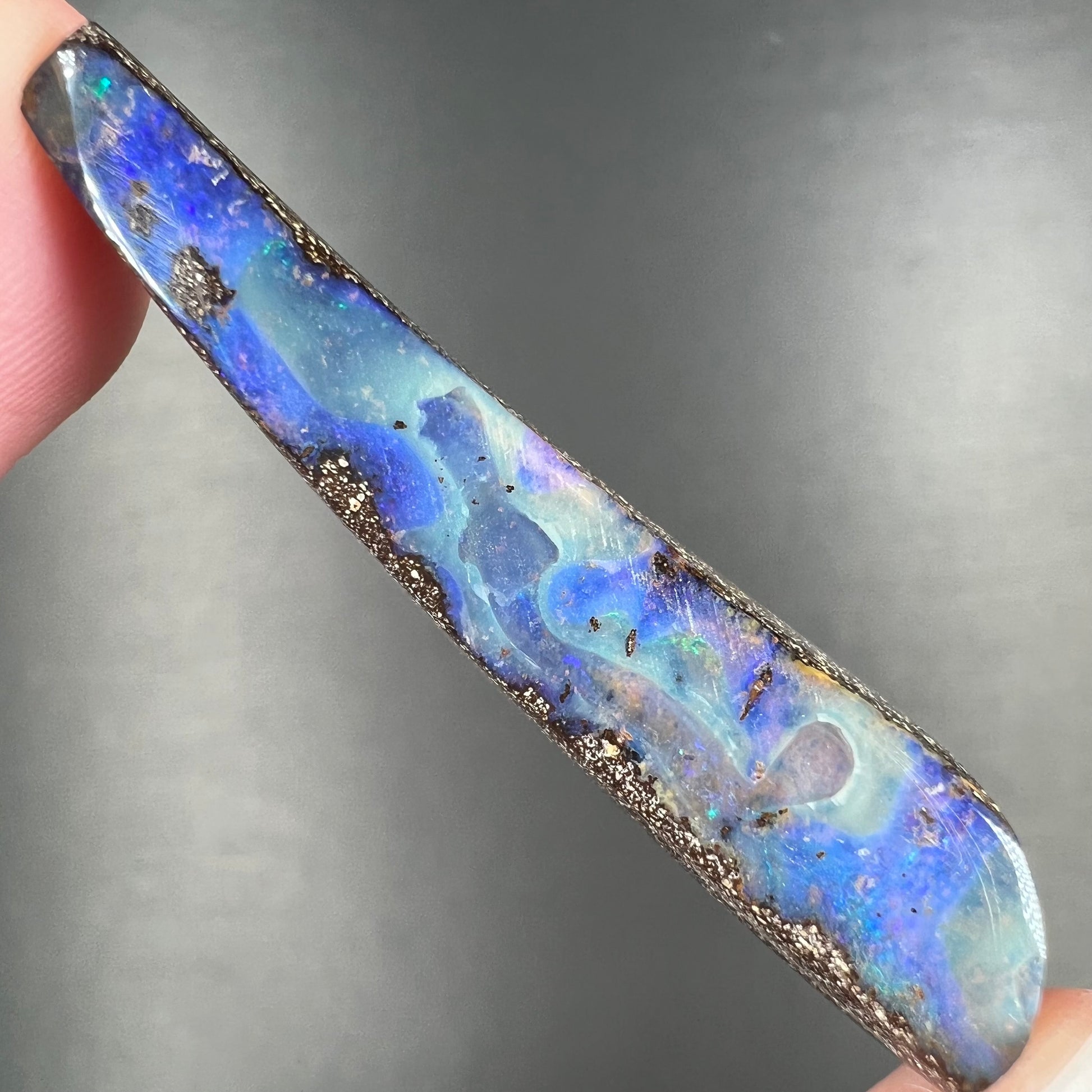 A loose, polished Quilpie boulder opal stone from Australia.  The stone is predominantly blue.