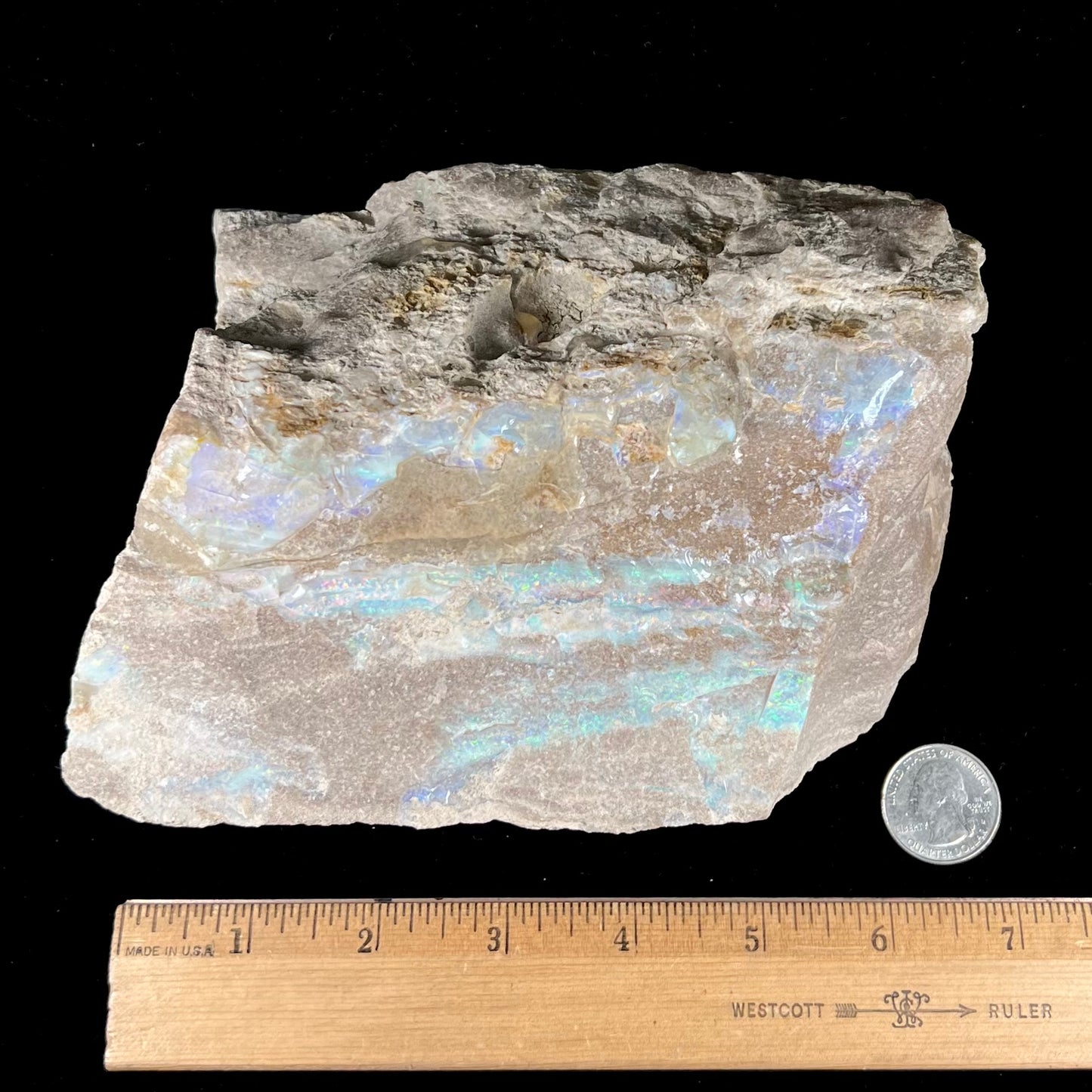 A rough Painted Lady boulder opal specimen that shows blue, green, and pinkish red colors.