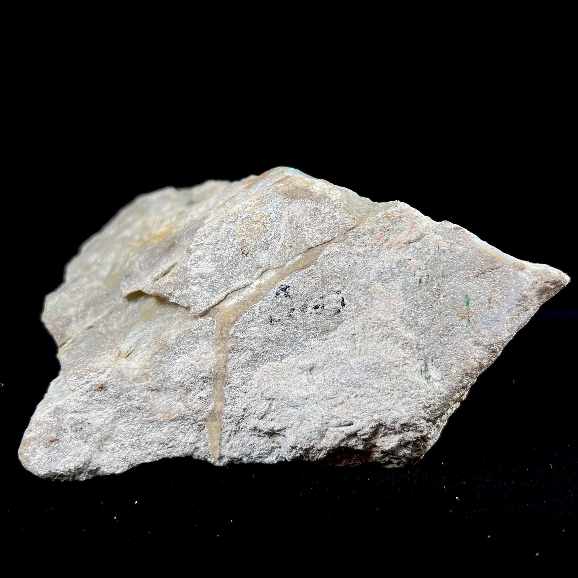 A rough Painted Lady boulder opal specimen that shows blue, green, and pinkish red colors.