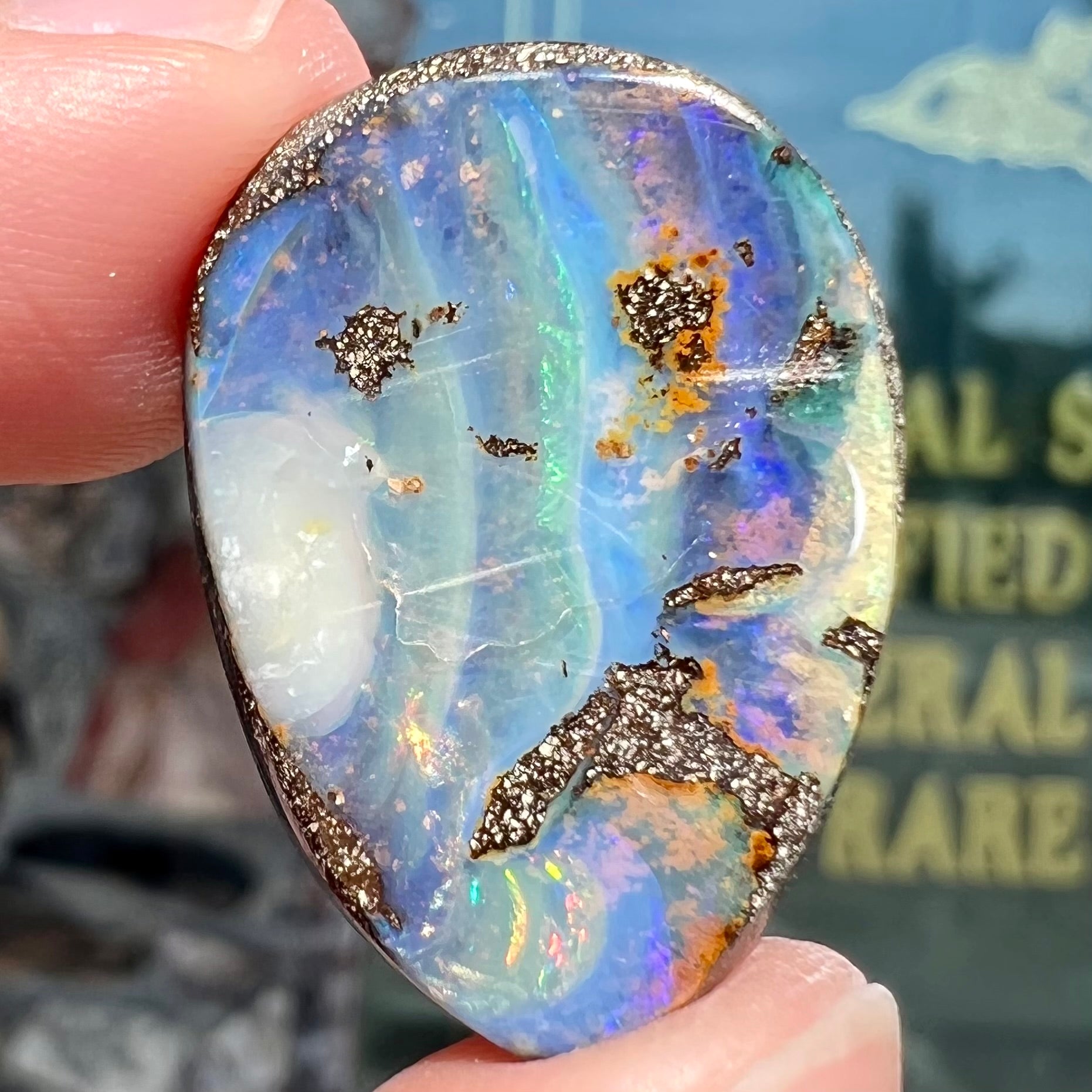 A loose, pear shaped Australian boulder opal.  The pattern on the opal resembles the face of a very sad man.