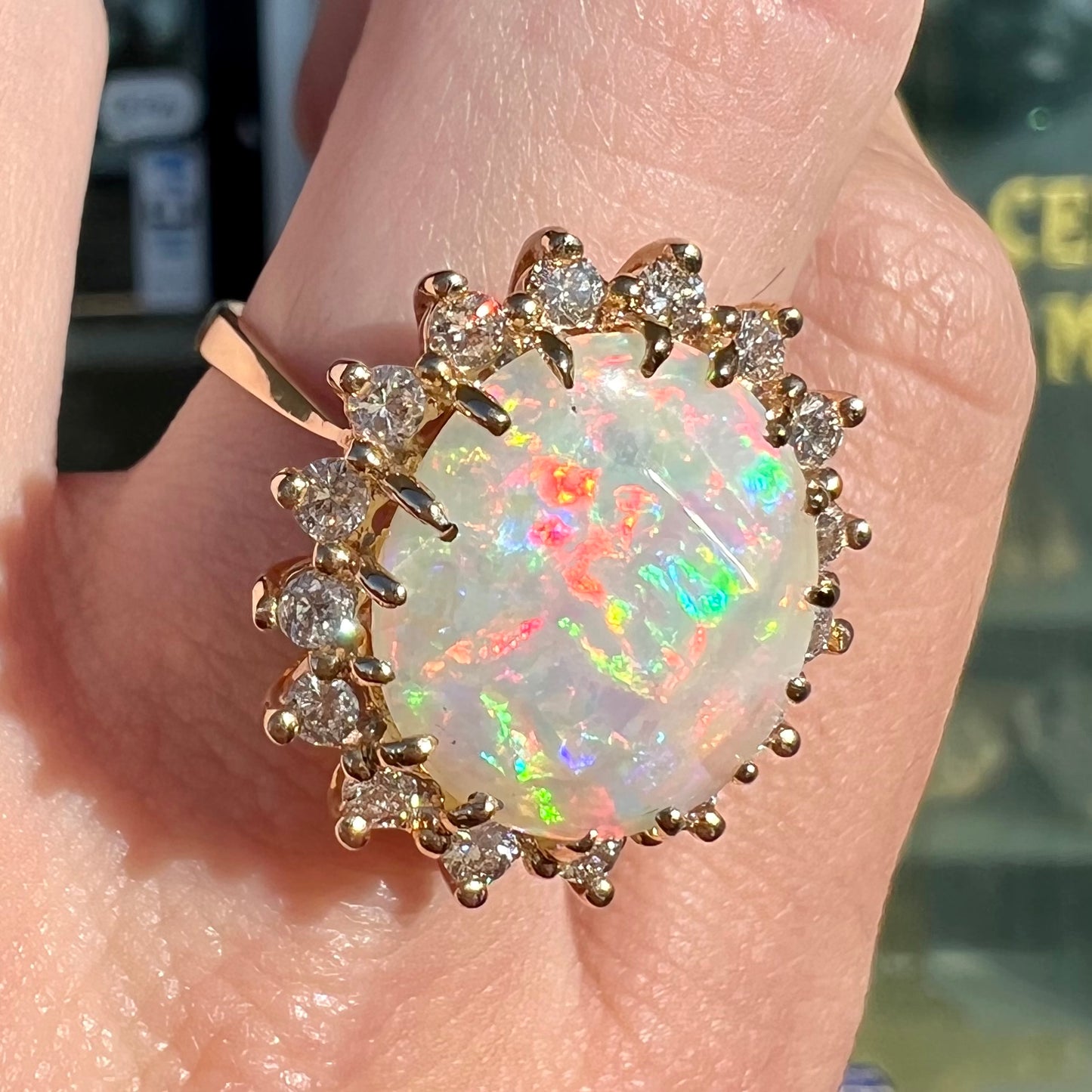 A ladies' diamond halo ring set with a Coober Pedy opalized seashell in yellow gold.