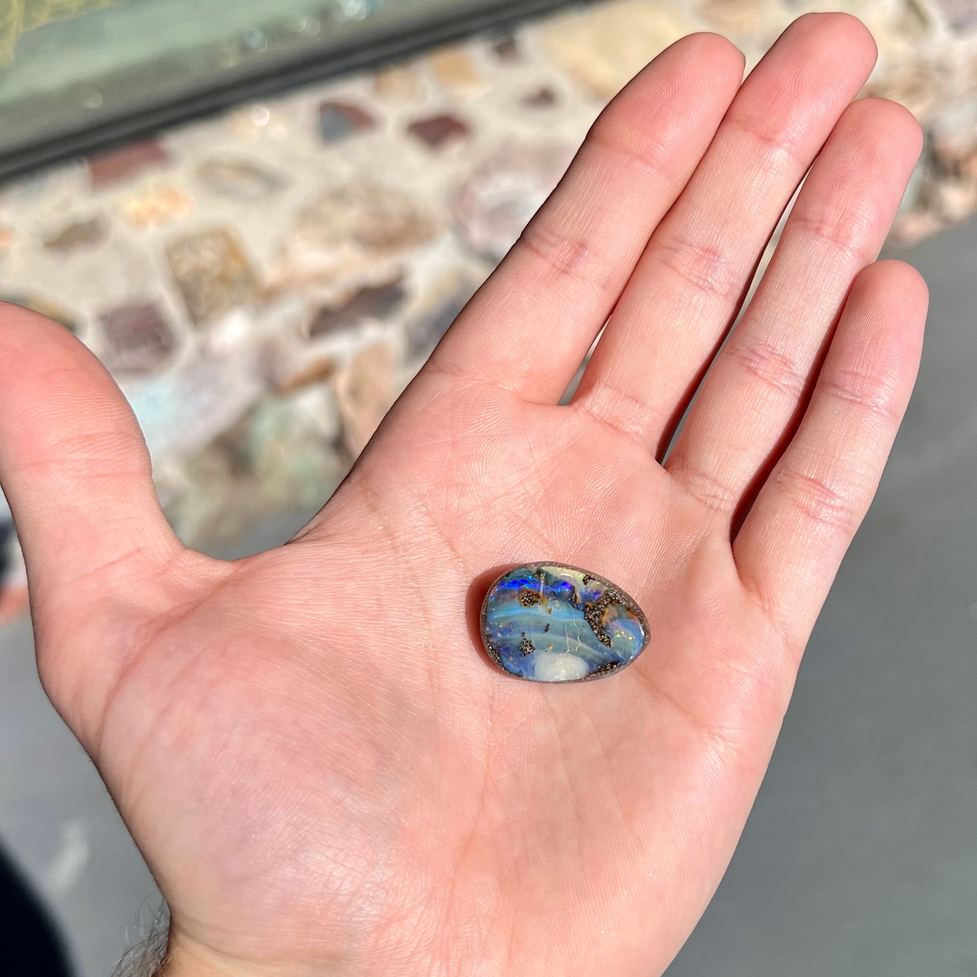 A loose, pear shaped Australian boulder opal.  The pattern on the opal resembles the face of a very sad man.
