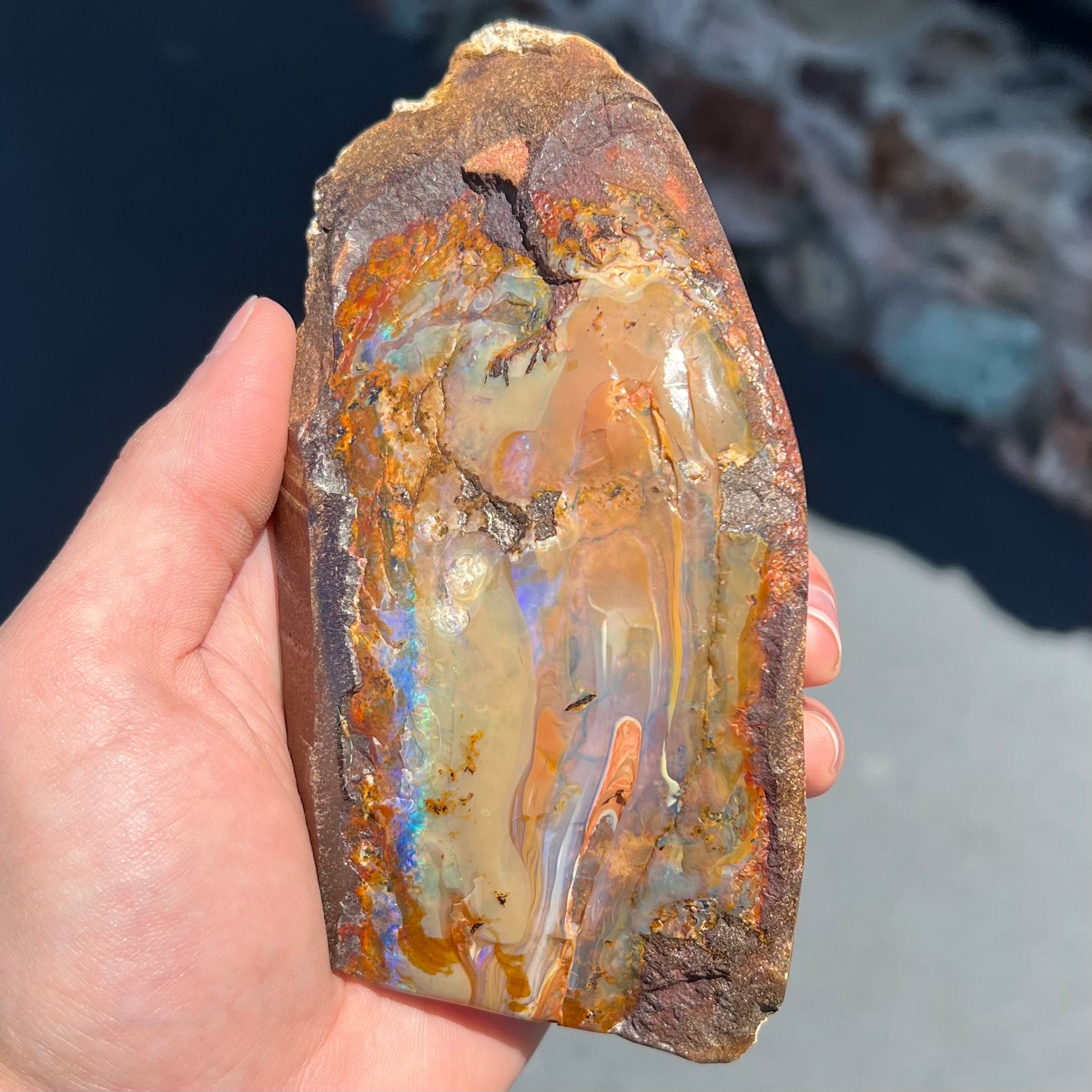 A polished Quilpie boulder opal specimen.  The stone has a stripe of bright blue, green, and purple.
