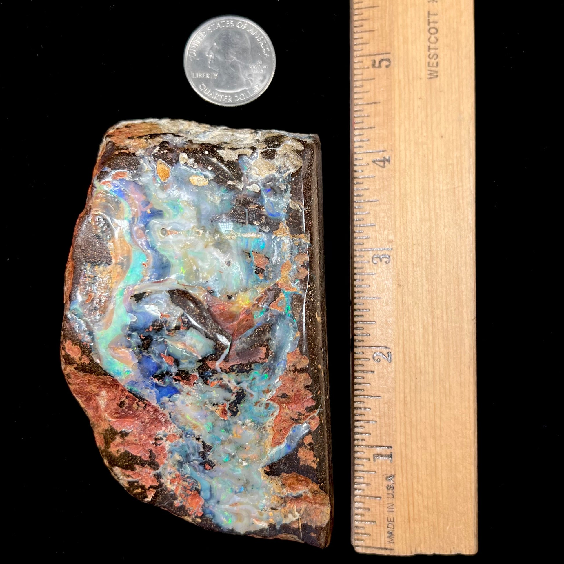 A hand-sized, polished Quilpie boulder opal specimen.  The stone shows blue, green, and orange flashes.