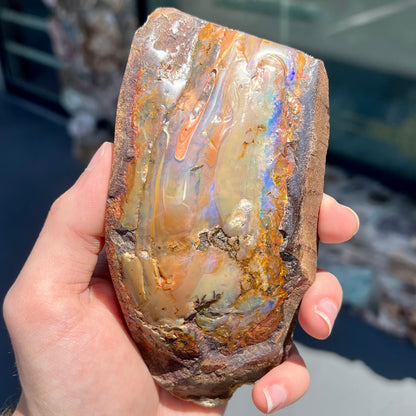 A polished Quilpie boulder opal specimen.  The stone has a stripe of bright blue, green, and purple.