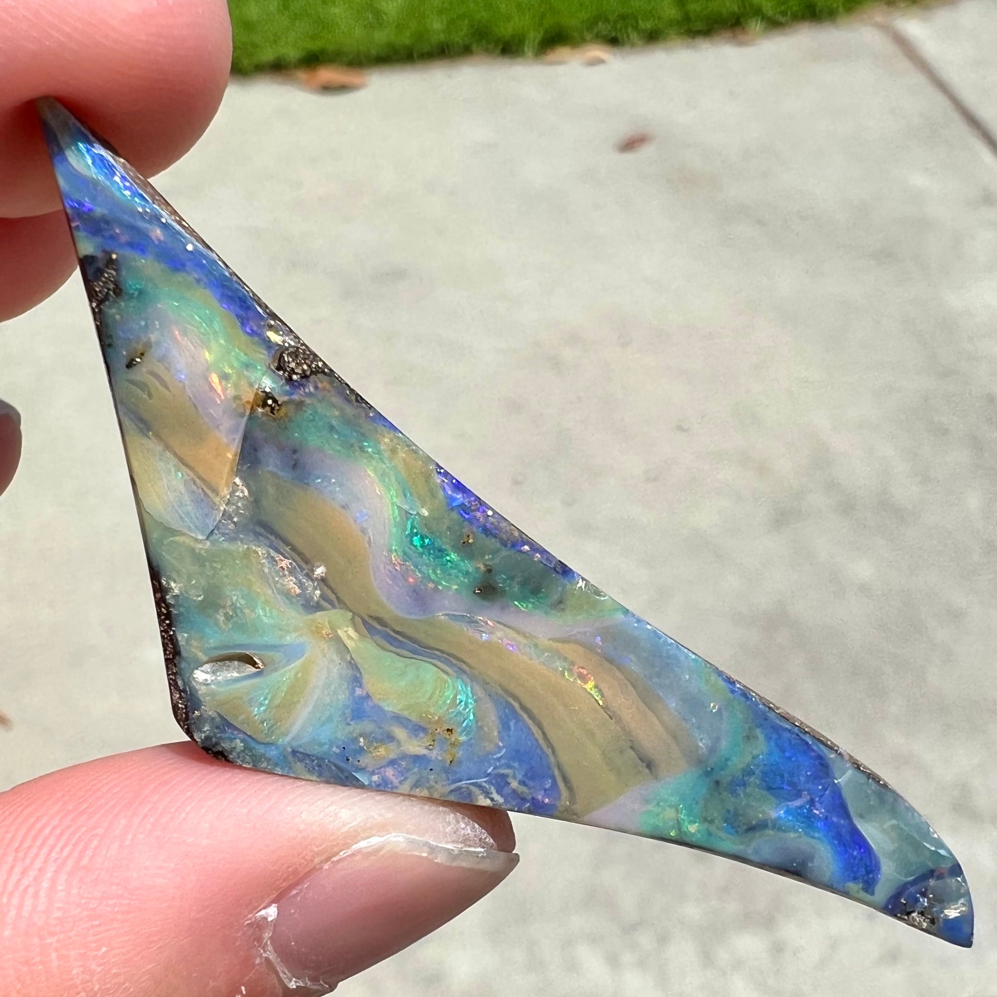 A loose, triangular shaped boulder opal stone from Queensland, Australia.