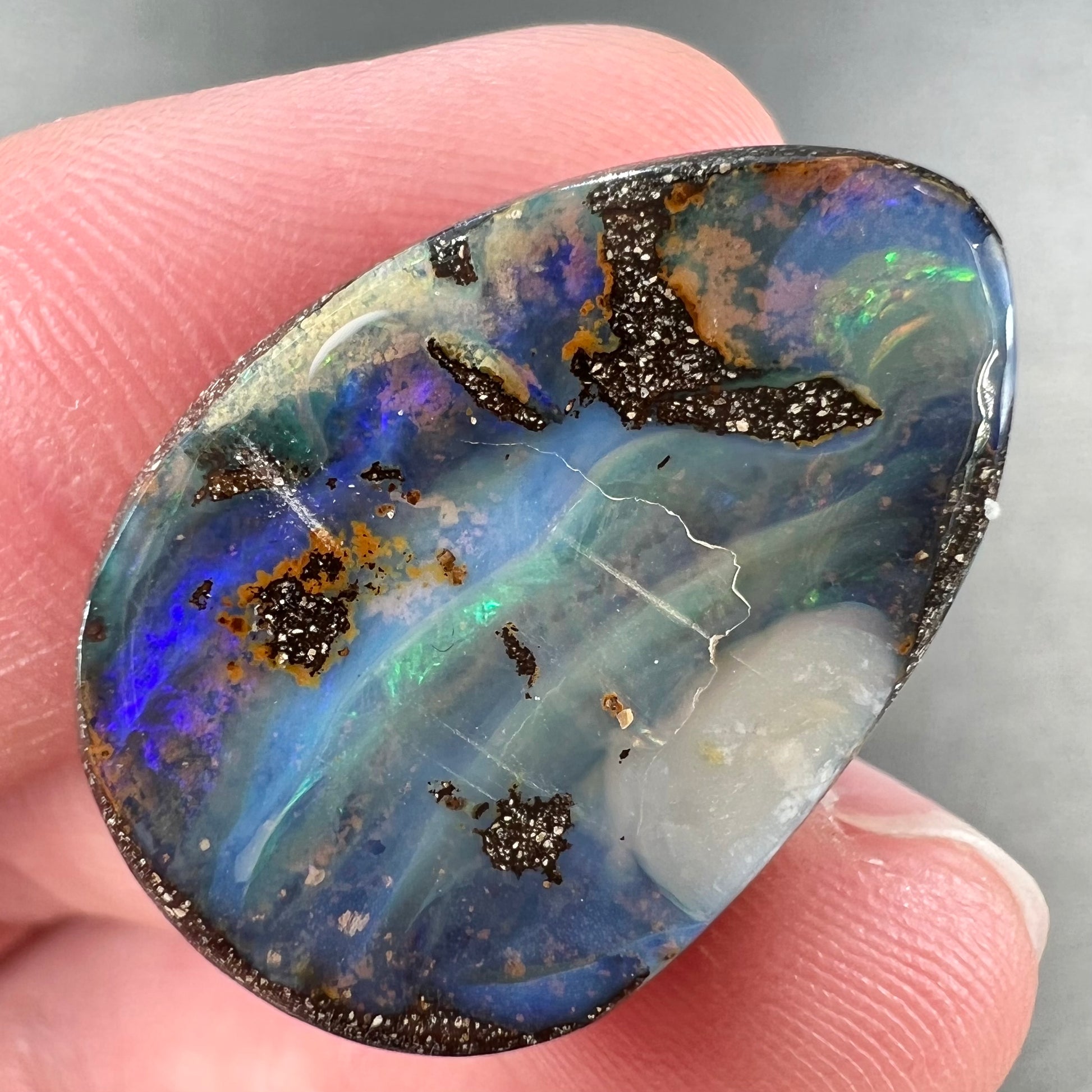 A loose, pear shaped Australian boulder opal.  The pattern on the opal resembles the face of a very sad man.